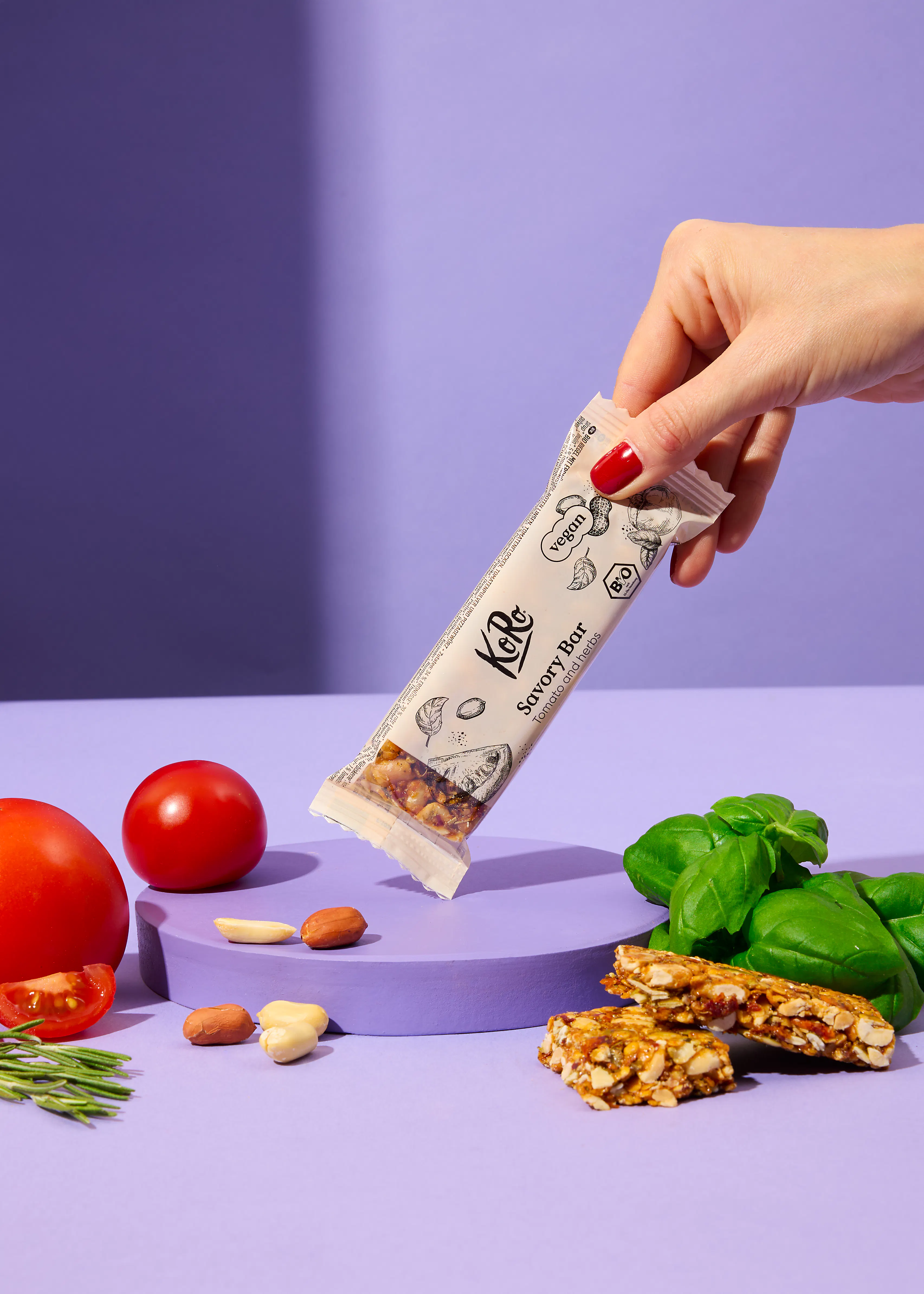 une main tient une barre savoureuse kale sur une table violette