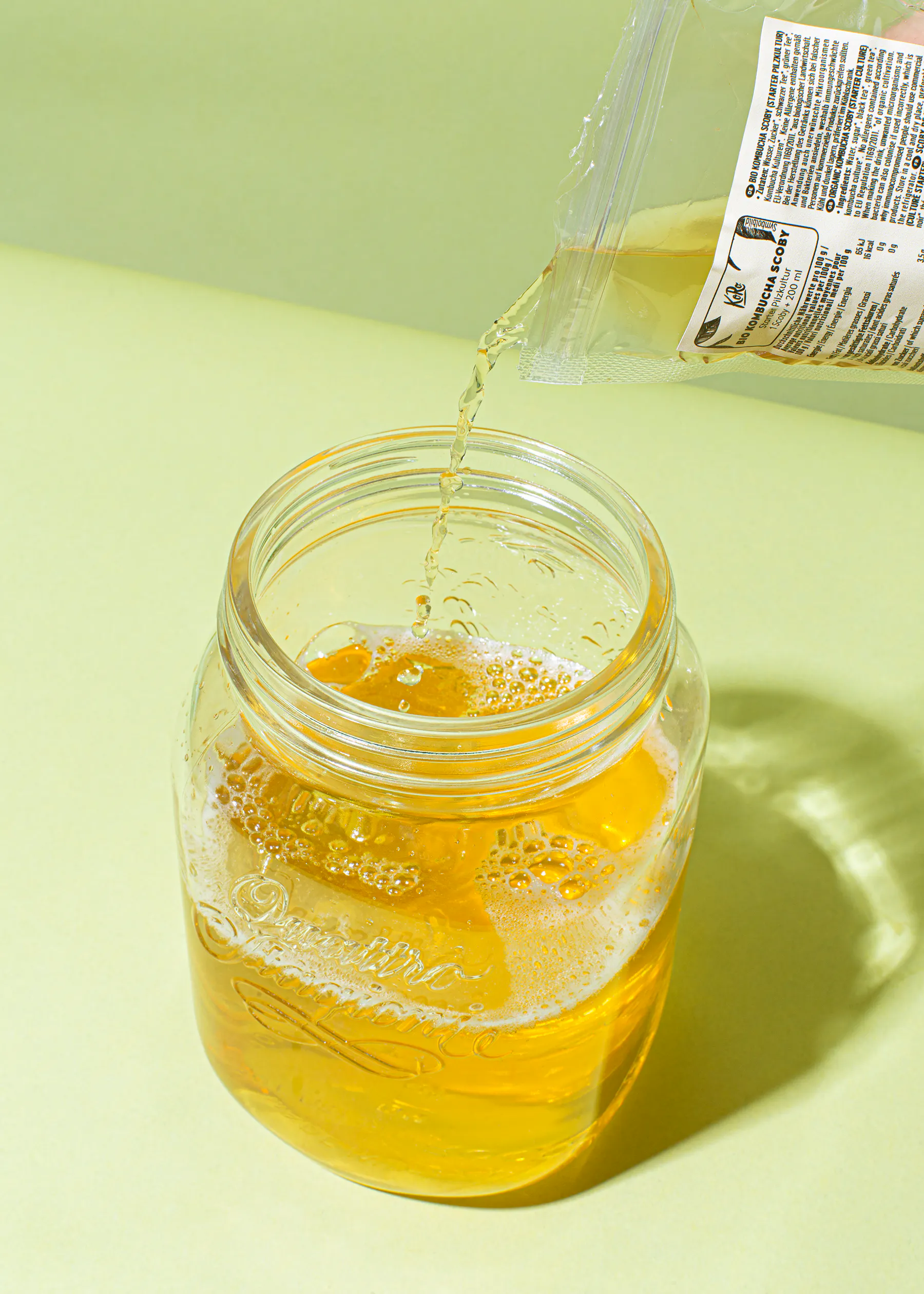 eine Person gießt etwas aus einem Plastikbeutel in ein Glas