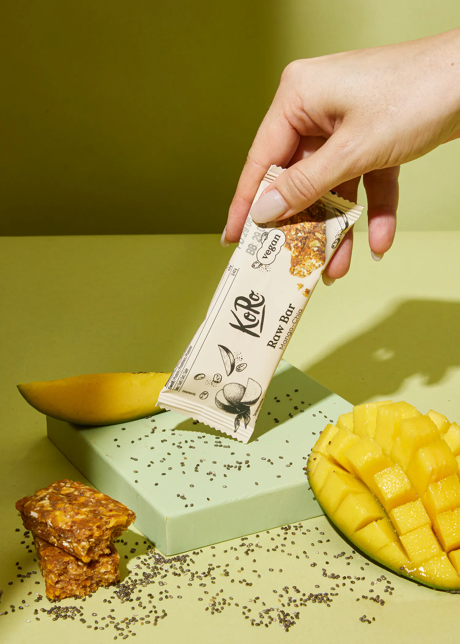 une personne tient une barre de graines de chia avec une mangue en arrière-plan