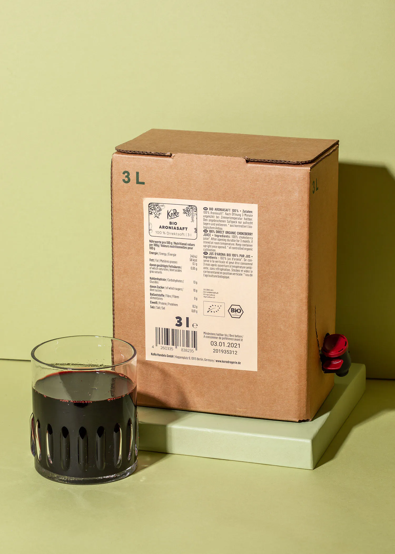 une boîte en carton de 3 litres est assise à côté d' un verre de liquide