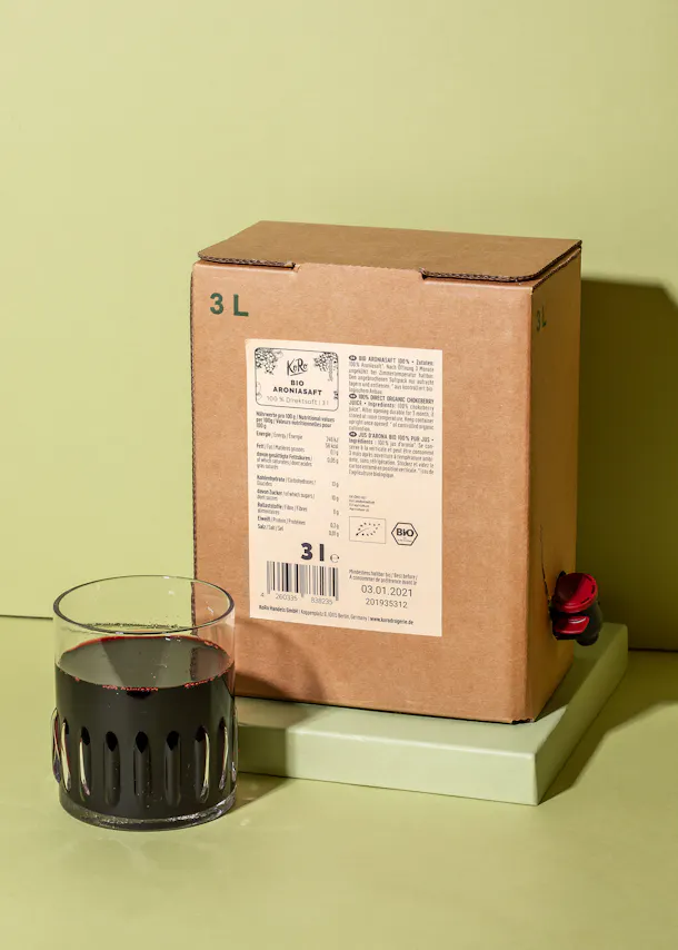 une boîte en carton de 3 litres est assise à côté d' un verre de liquide