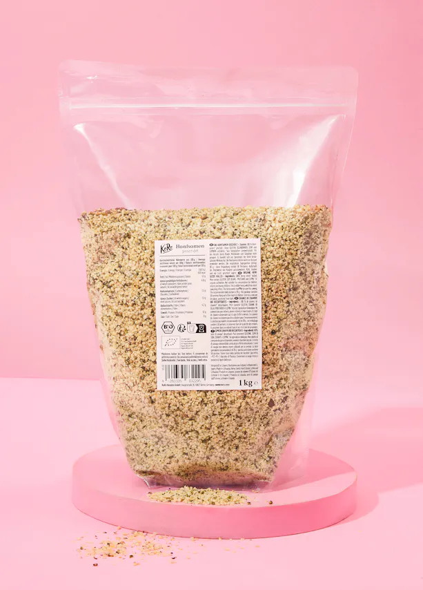 un sac en plastique rempli de graines de chanvre est posé sur une table rose
