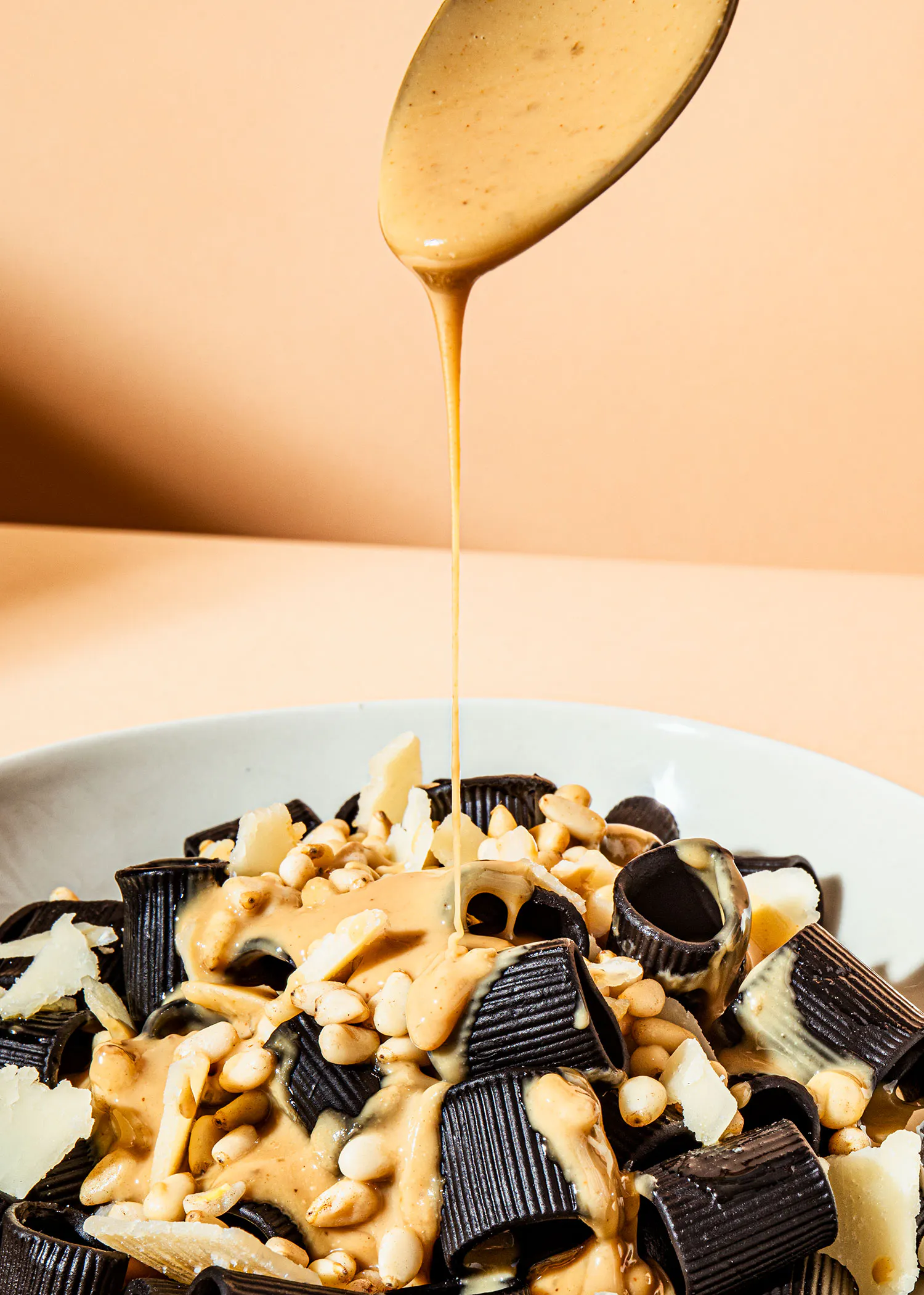 a bowl of pasta with sauce being poured on it