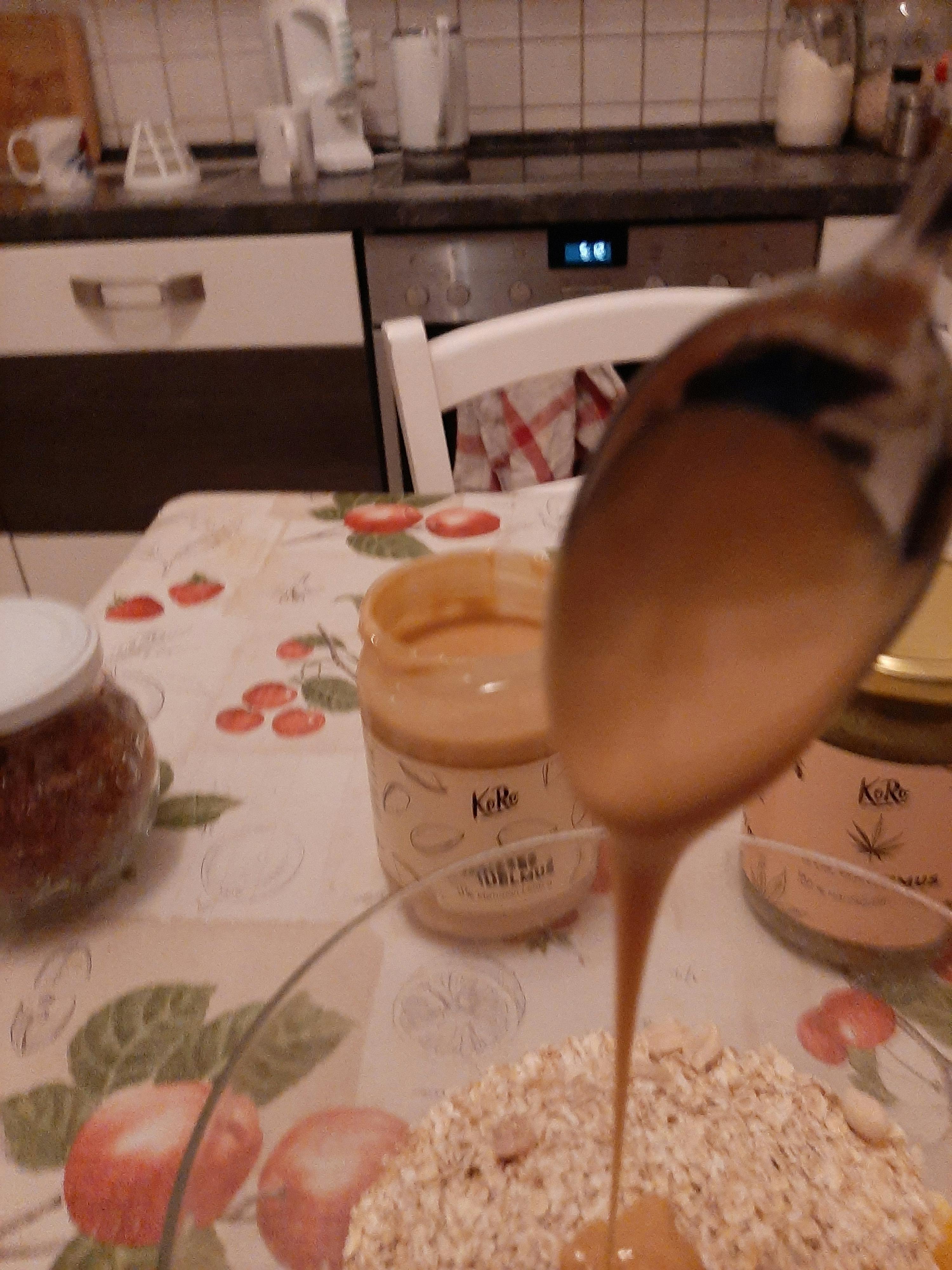 un cucchiaio di burro di arachidi viene versato in un barattolo di kelly