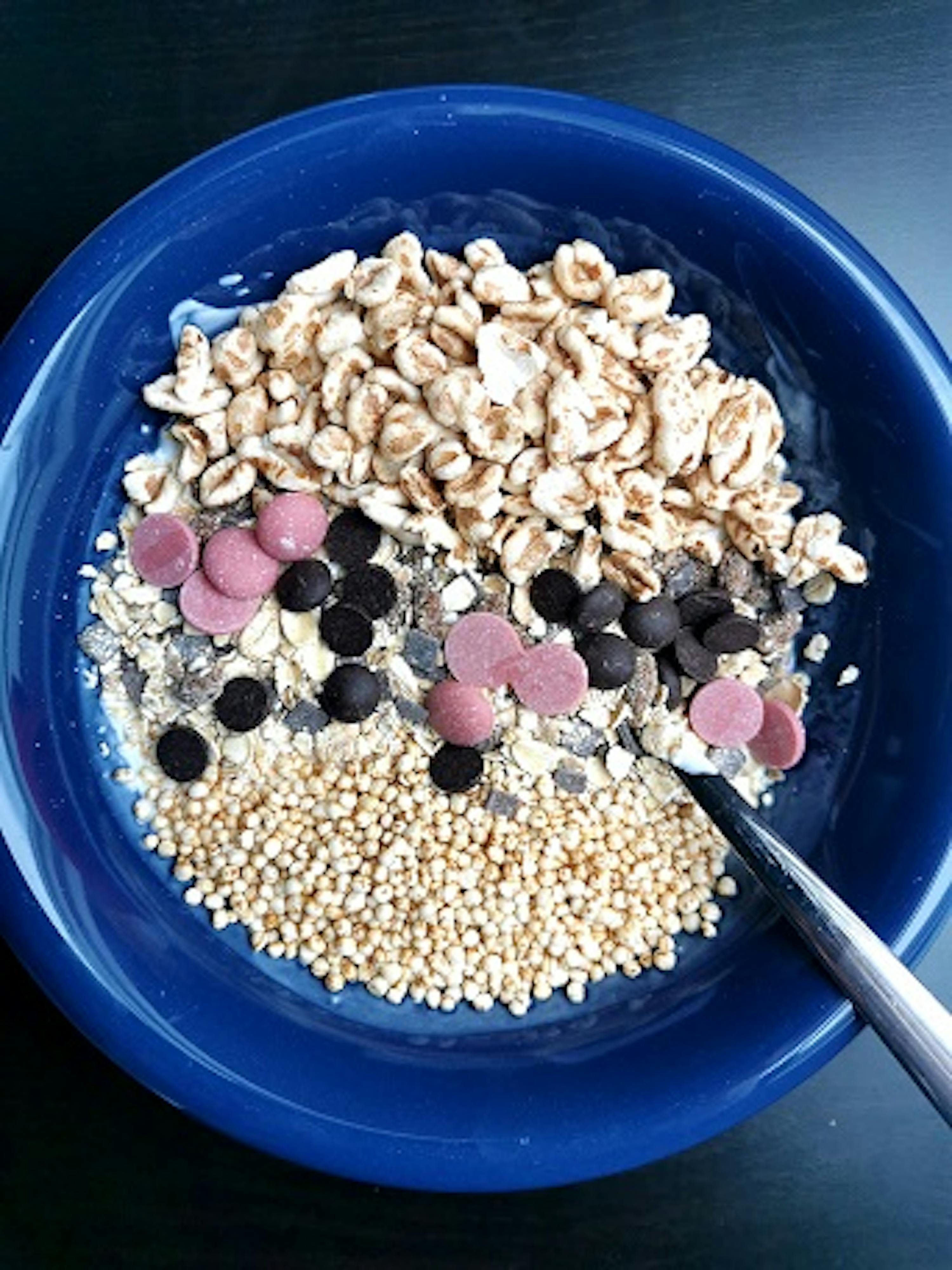 eine blaue Schüssel mit Haferflocken und Schokoladenstückchen mit einem Löffel darin