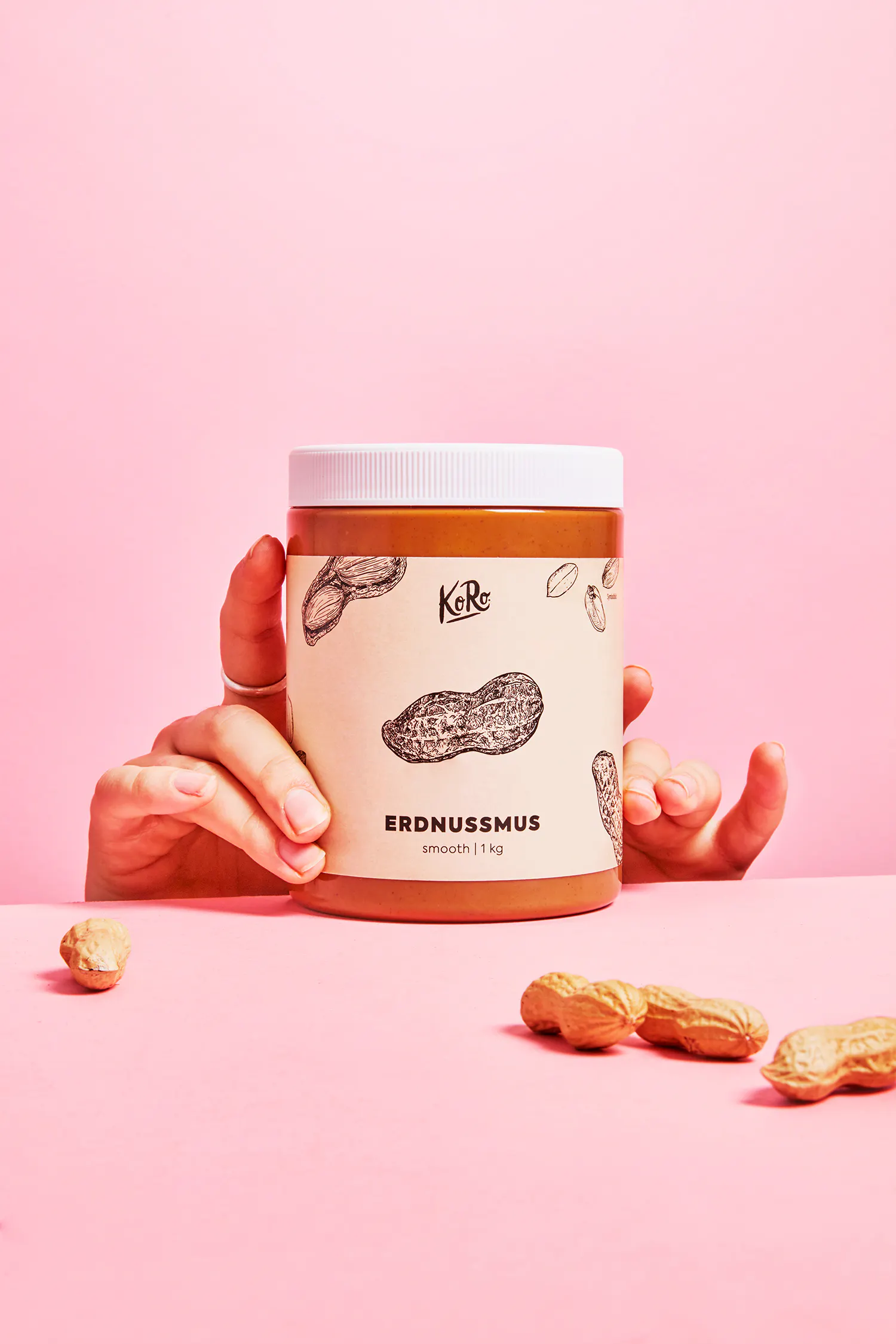 une personne tient un bocal de beurre d' arachide sur fond rose