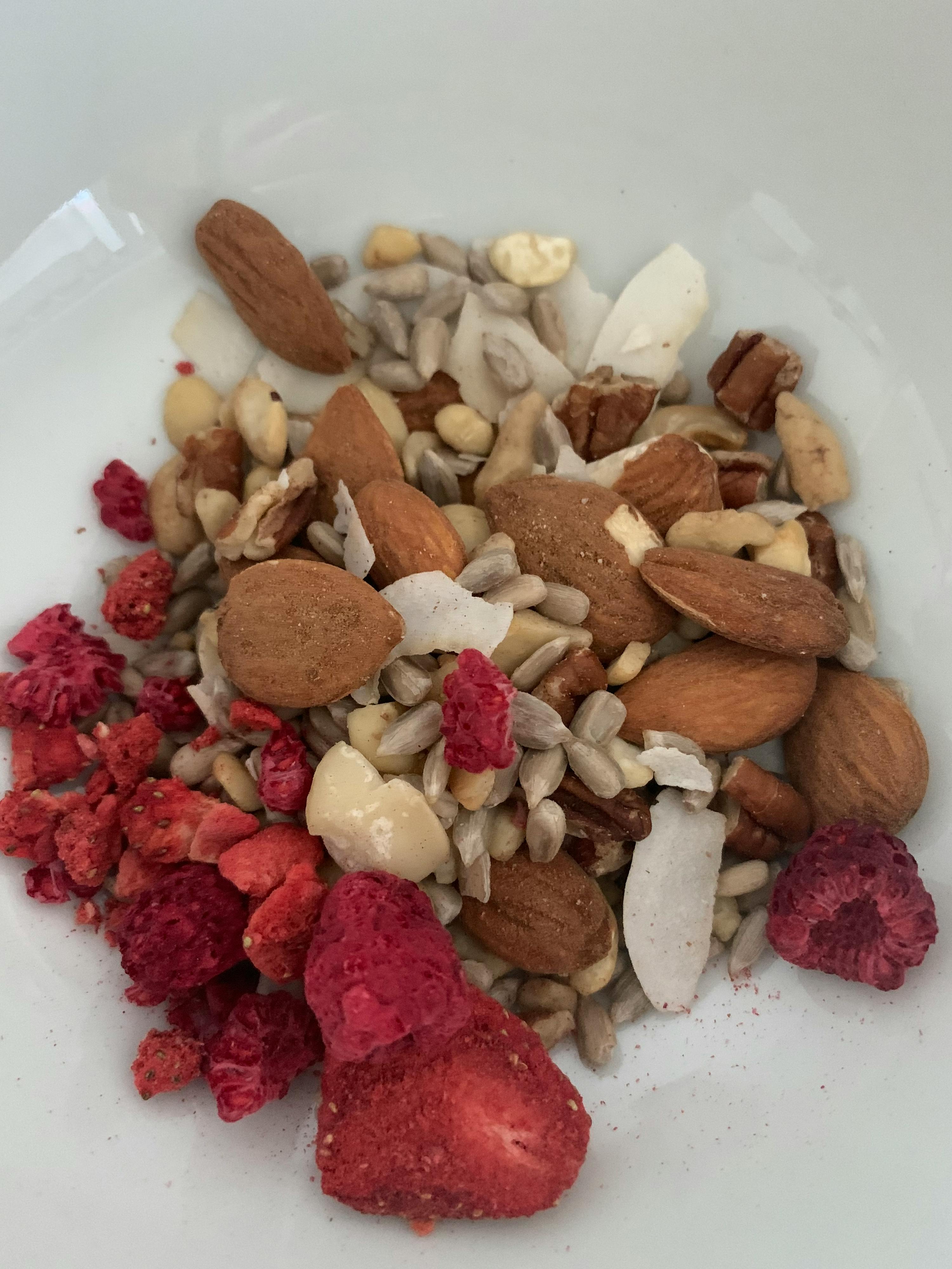 eine weiße Schüssel mit einer Mischung aus Nüssen und getrockneten Himbeeren