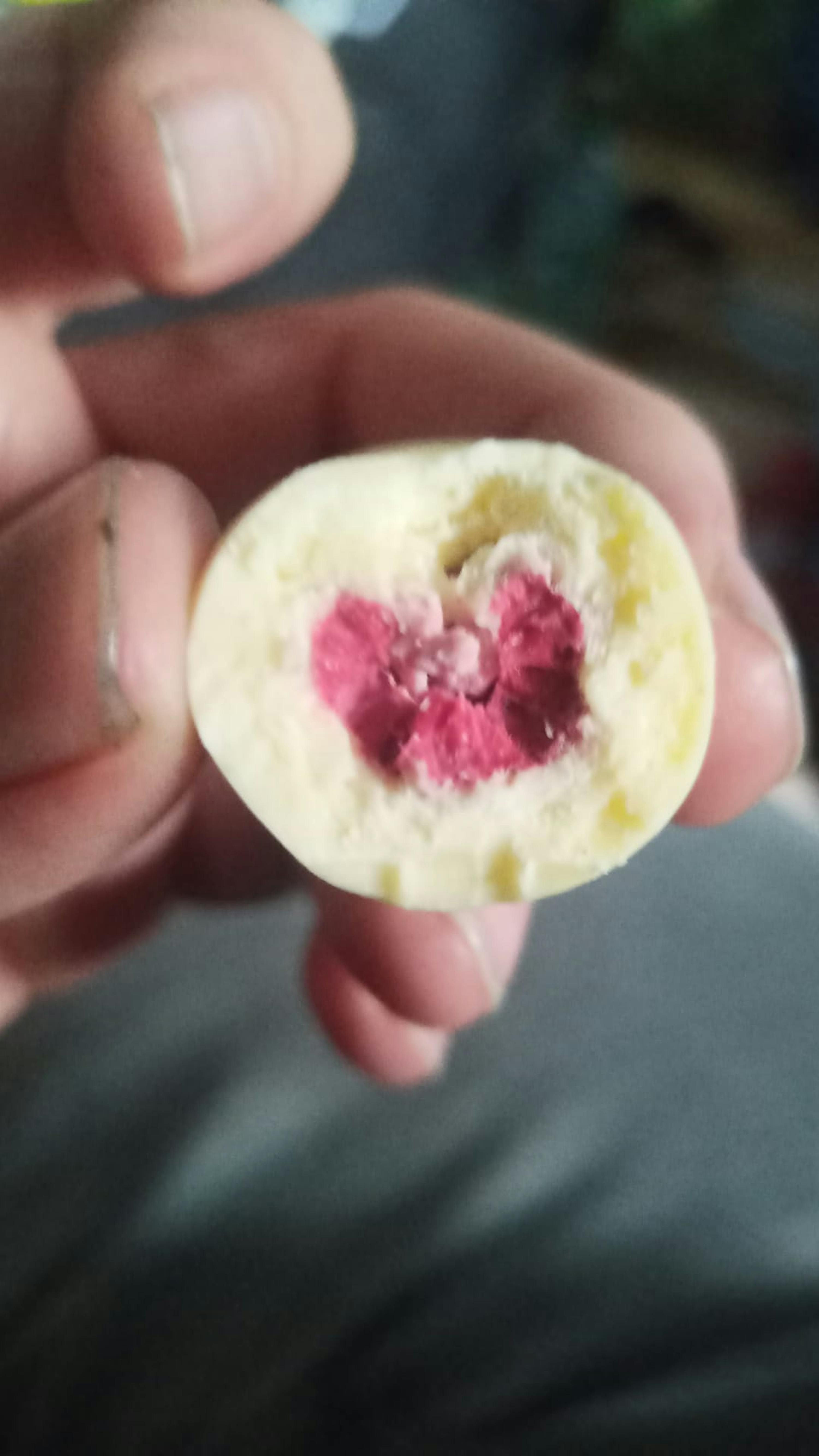 eine Person hält einen Stück Schokolade mit einem roten Herzen darin