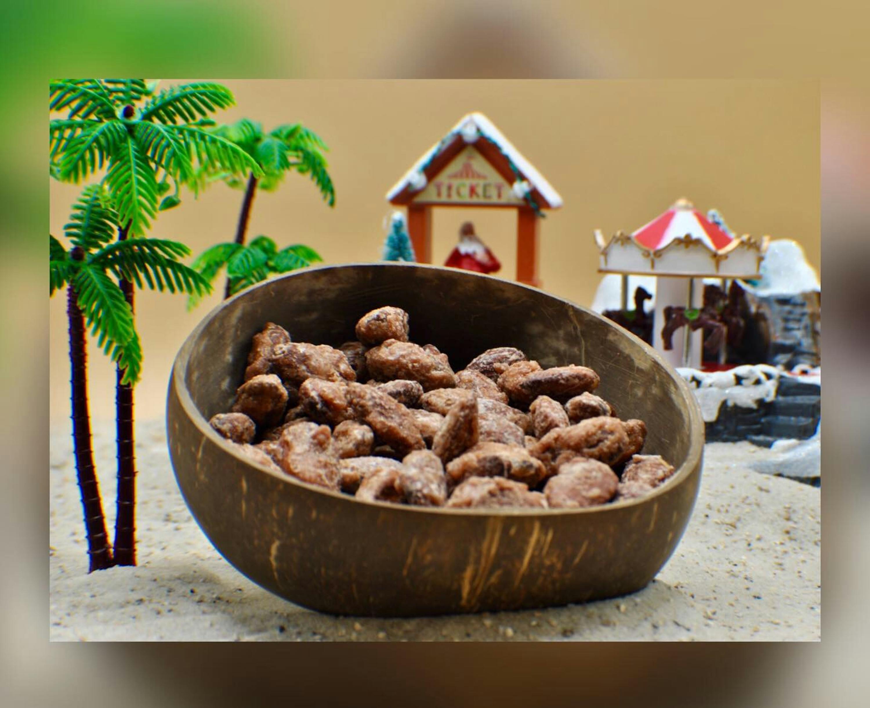 un bol en bois rempli de noix de coco avec une maison en pain d' épices en arrière-plan