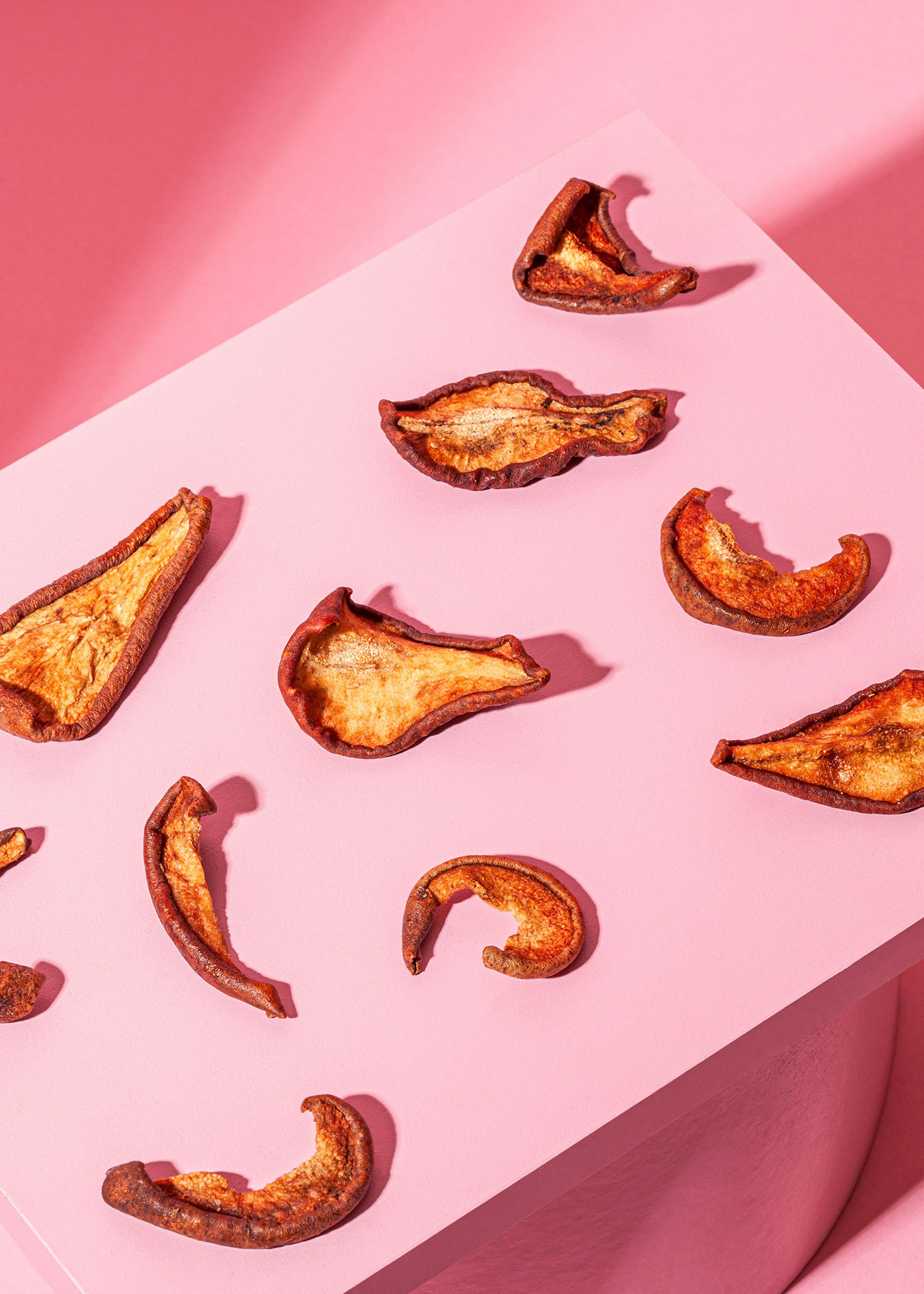 a bunch of dried fruit slices on a pink surface