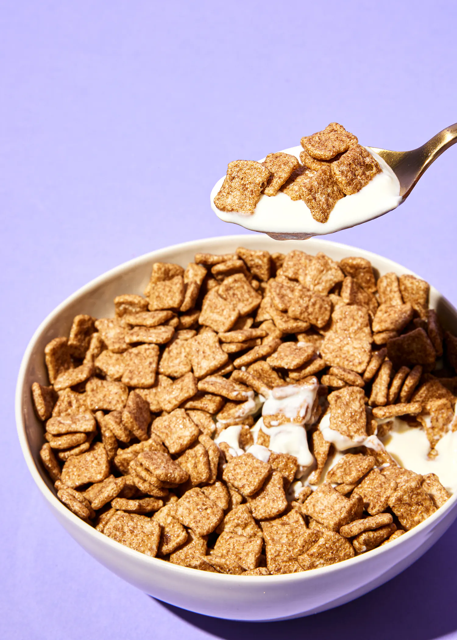 une cuillère remplie de céréales et de lait sur un fond violet