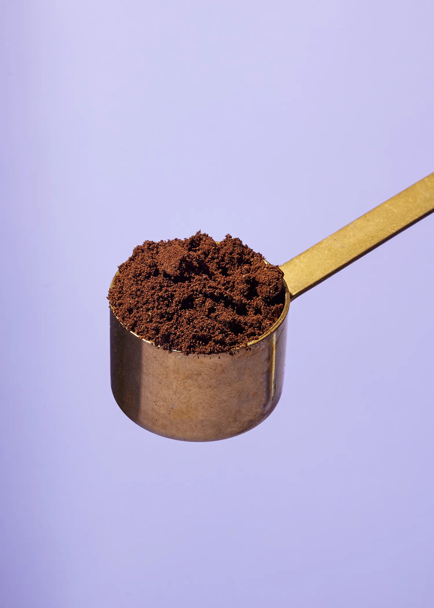 une cuillère remplie de poudre de café sur un fond violet