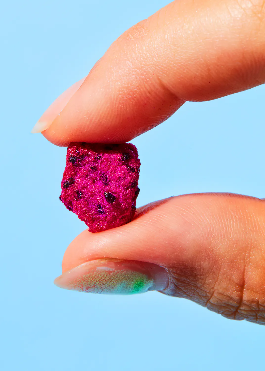 une personne tient un morceau de fruit du dragon entre ses doigts