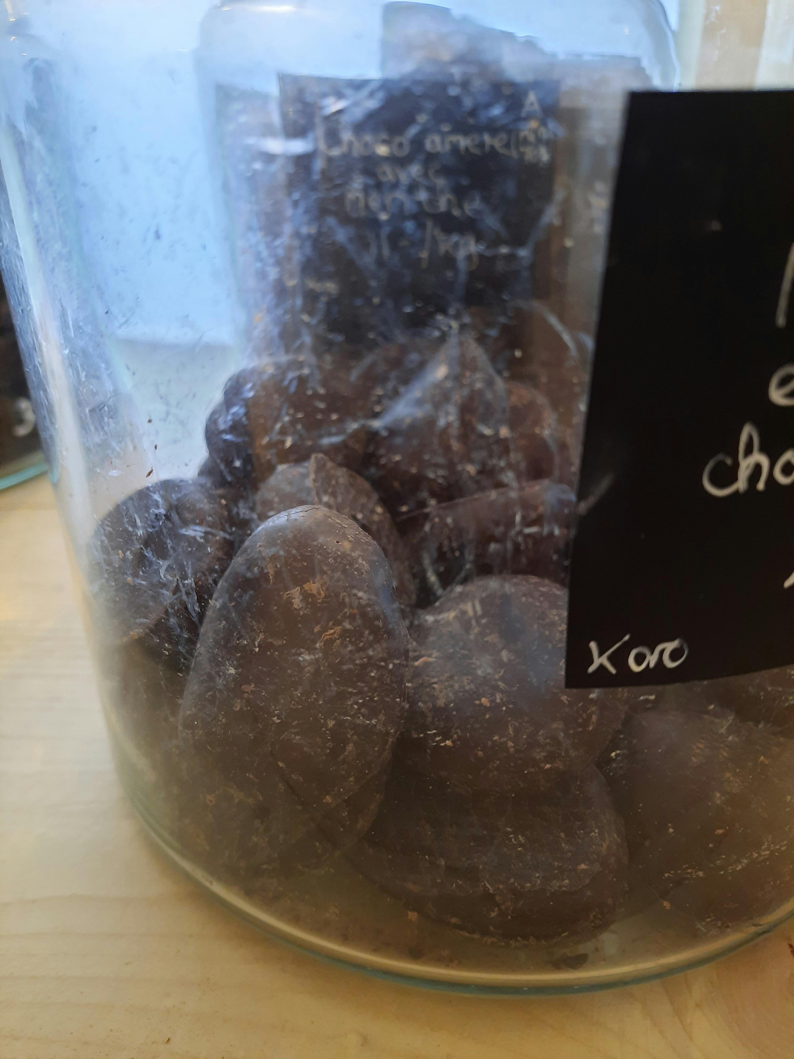 un bocal en verre rempli d' amandes enrobées de chocolat noir