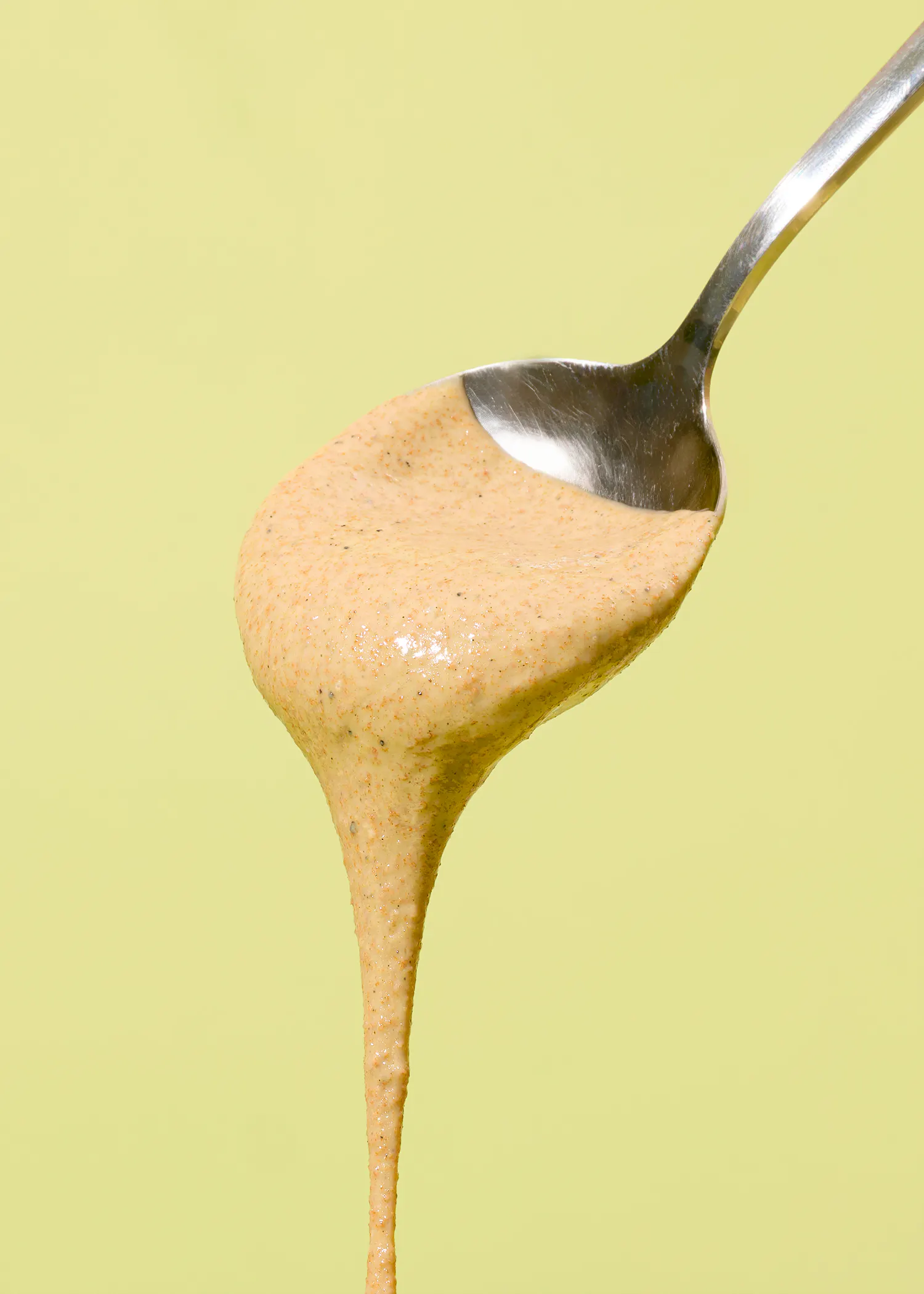 une cuillère remplie de sauce sur un fond jaune