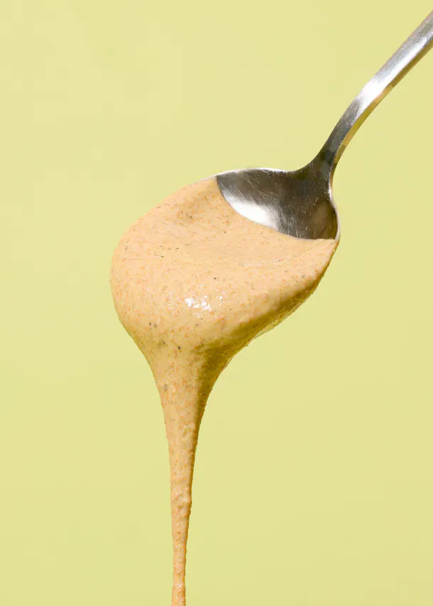 une cuillère remplie de sauce sur un fond jaune