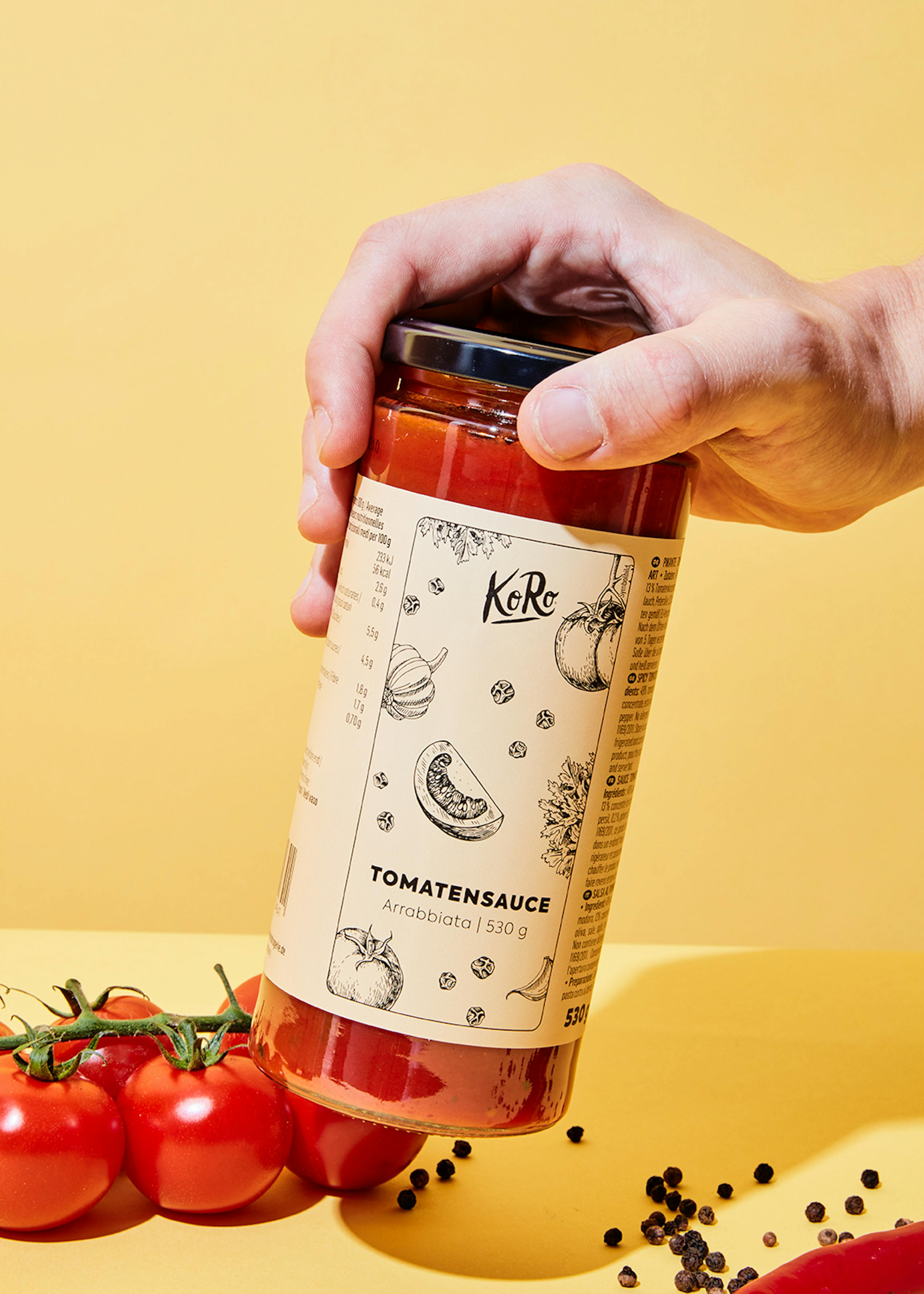 a person is holding a jar of tomato sauce