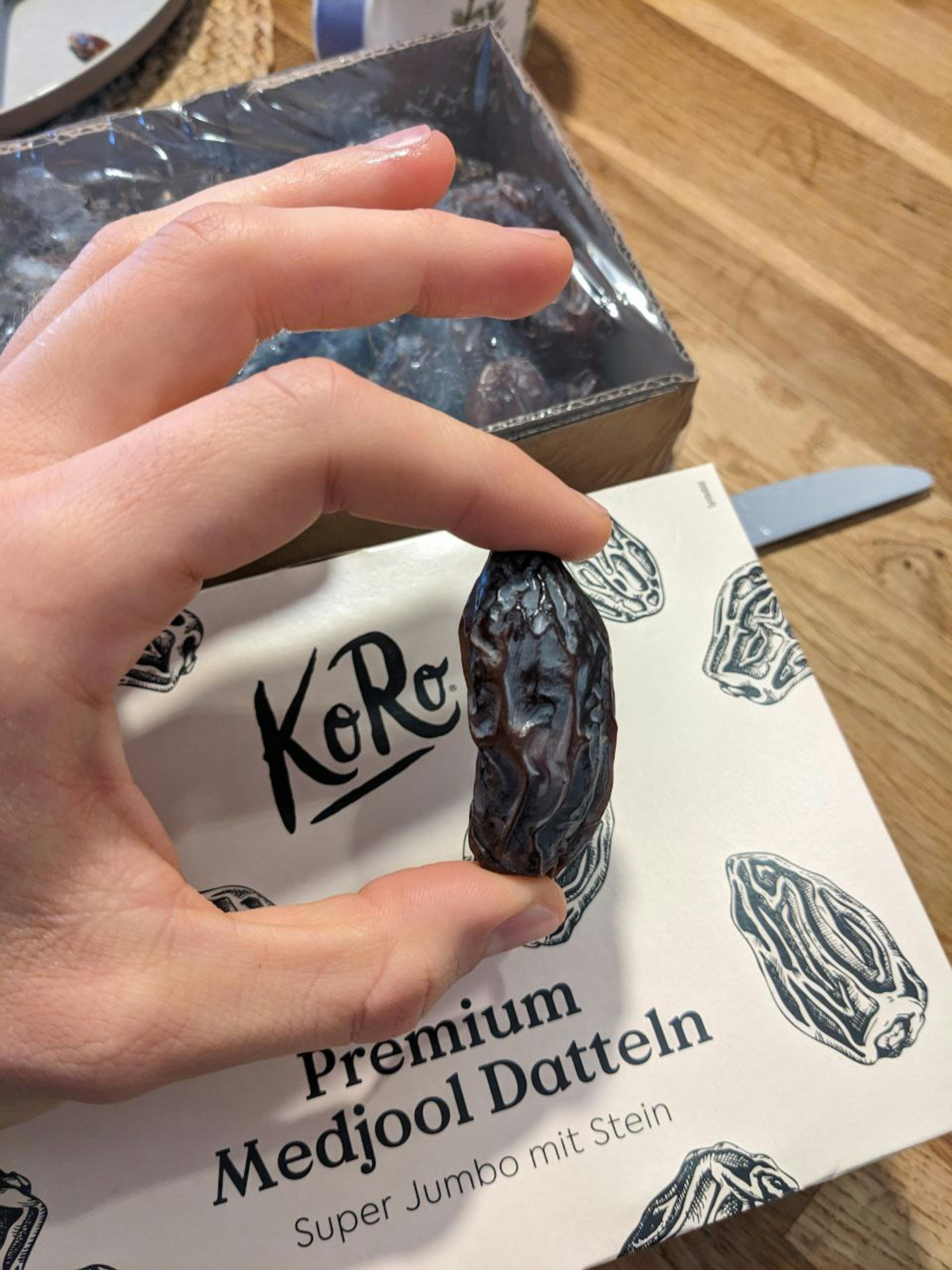 una persona tiene in mano un medjool premium super jumbo mit stein