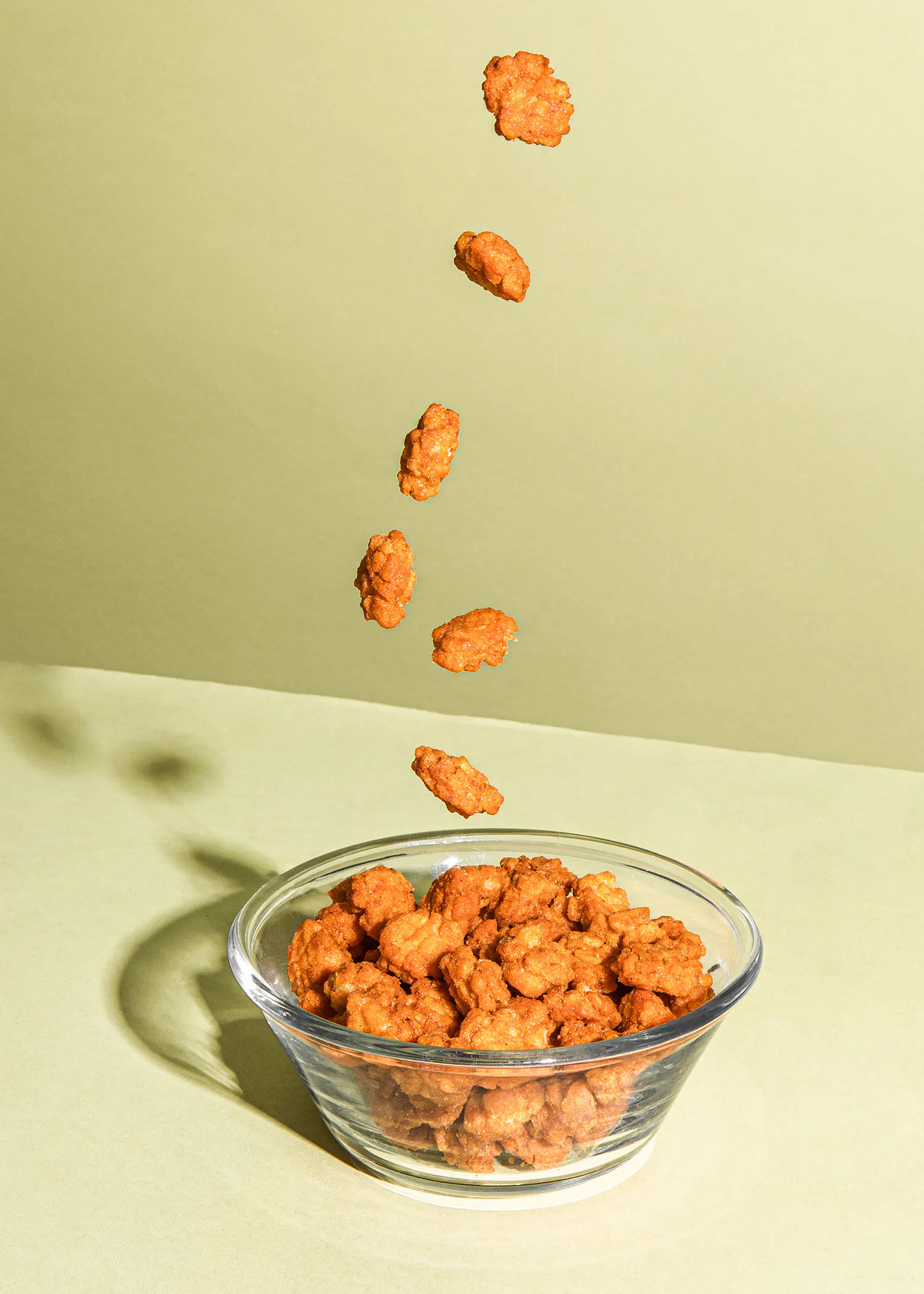 un bol en verre rempli de cacahuètes avec des cacahuètes tombant dedans