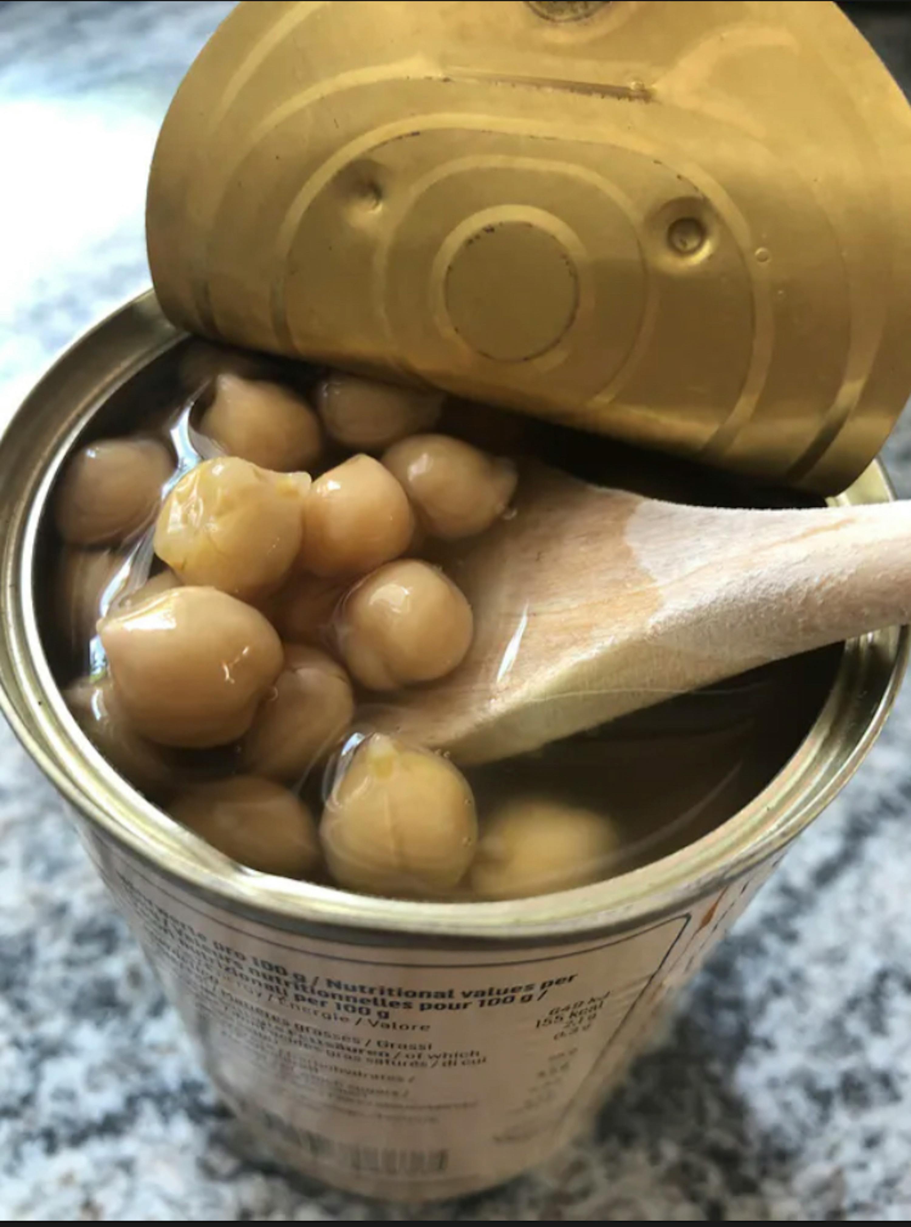 a can of chickpeas has a wooden spoon in it