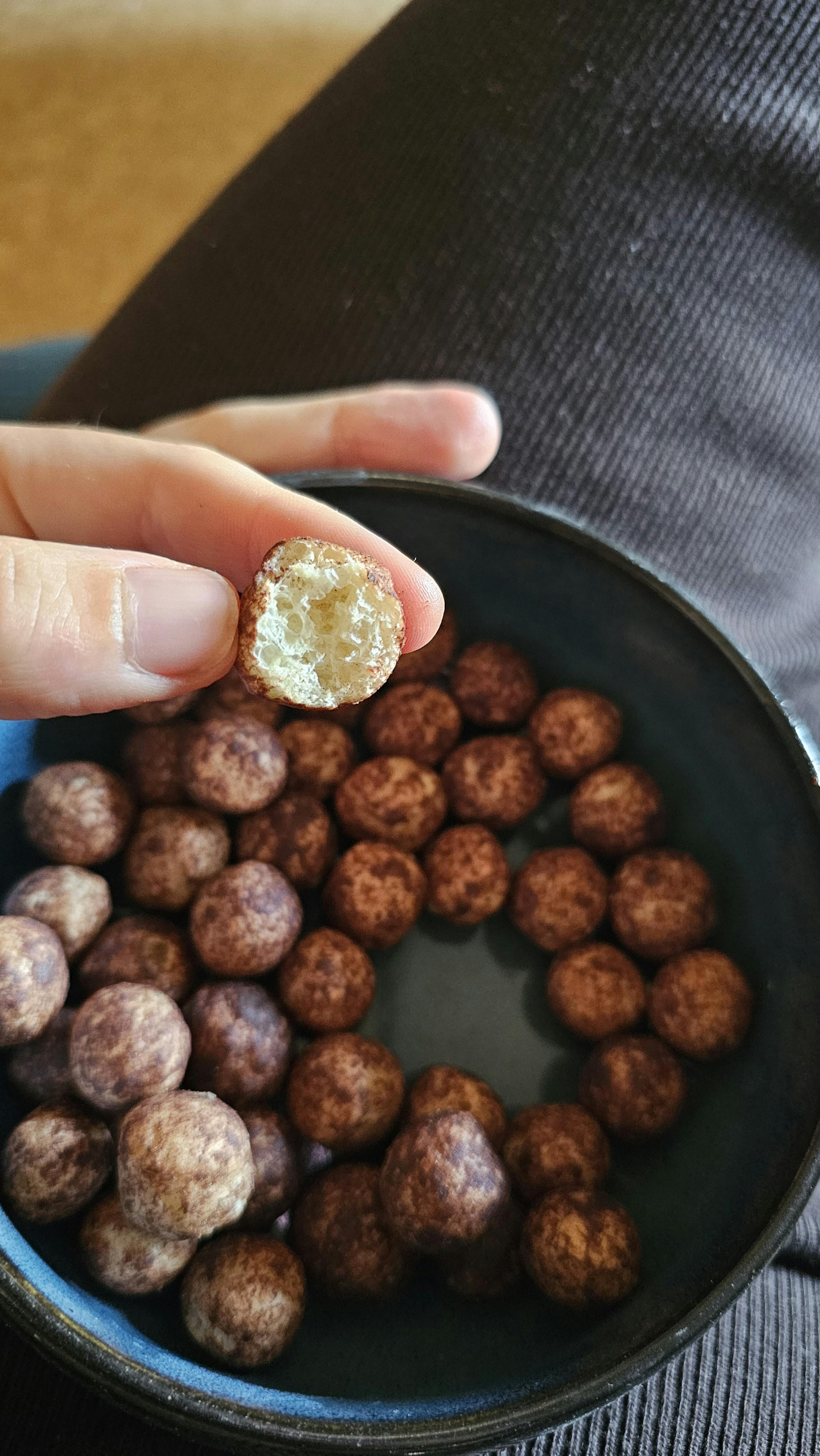 une personne tient une balle de céréales au chocolat à côté d' un bol de céréales