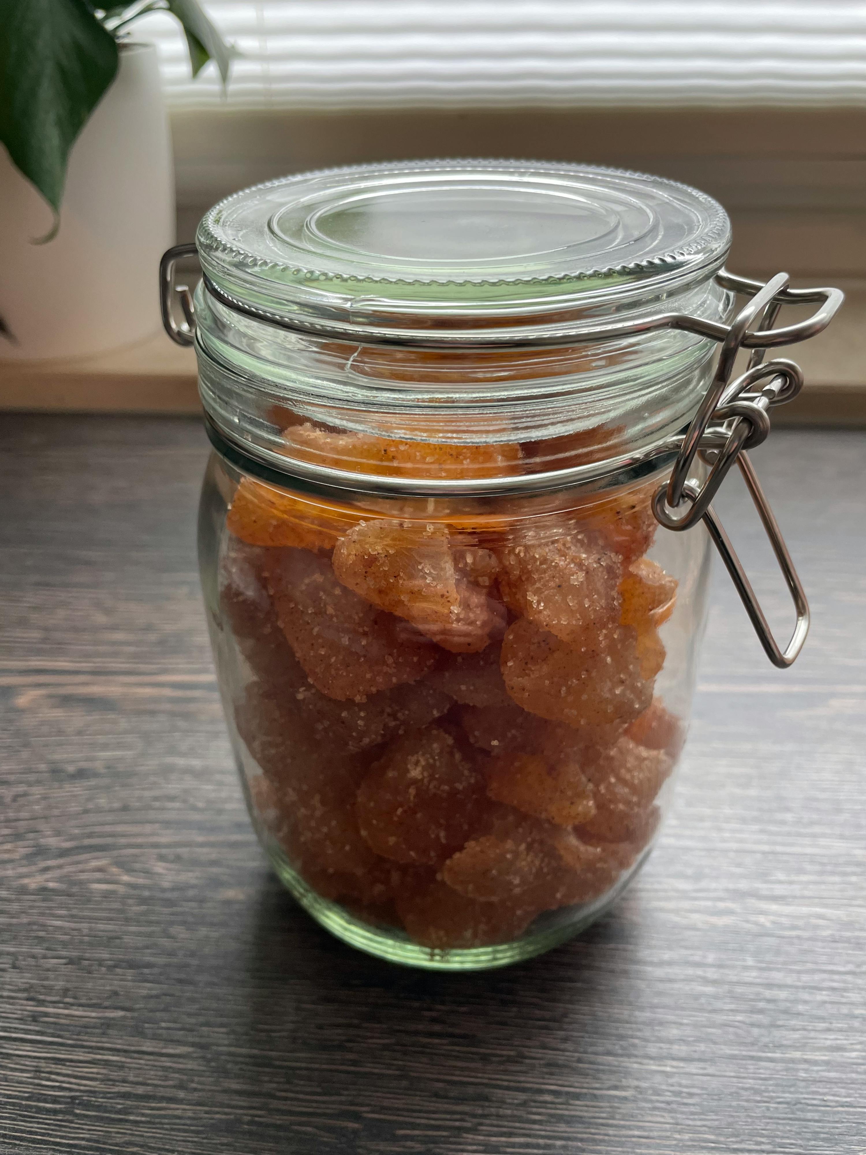 un bocal en verre rempli de bonbons est posé sur une table en bois