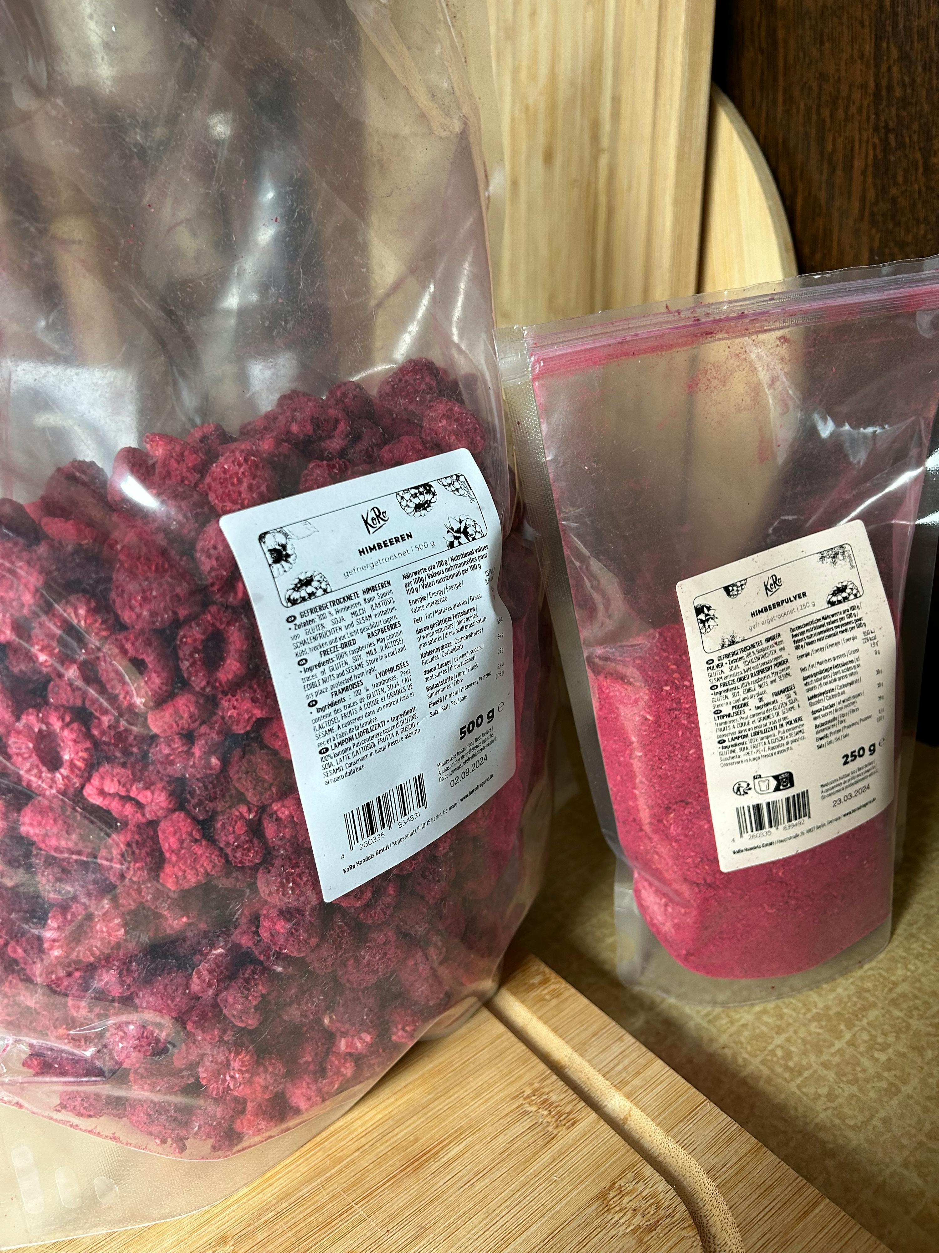 a bag of powdered raspberry next to a bag of dried raspberries