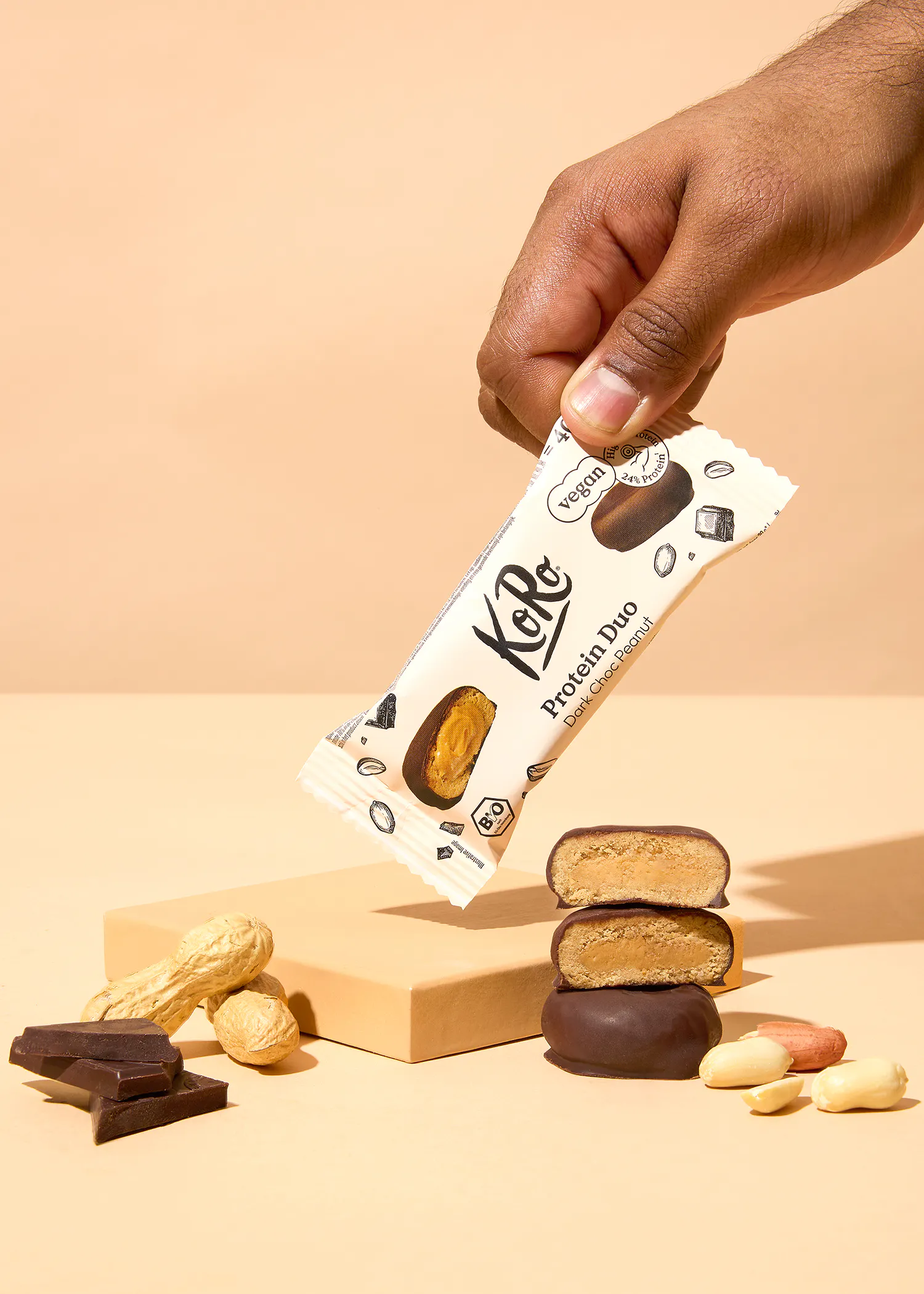 une personne tient une barre de protéines avec des cacahuètes dessus