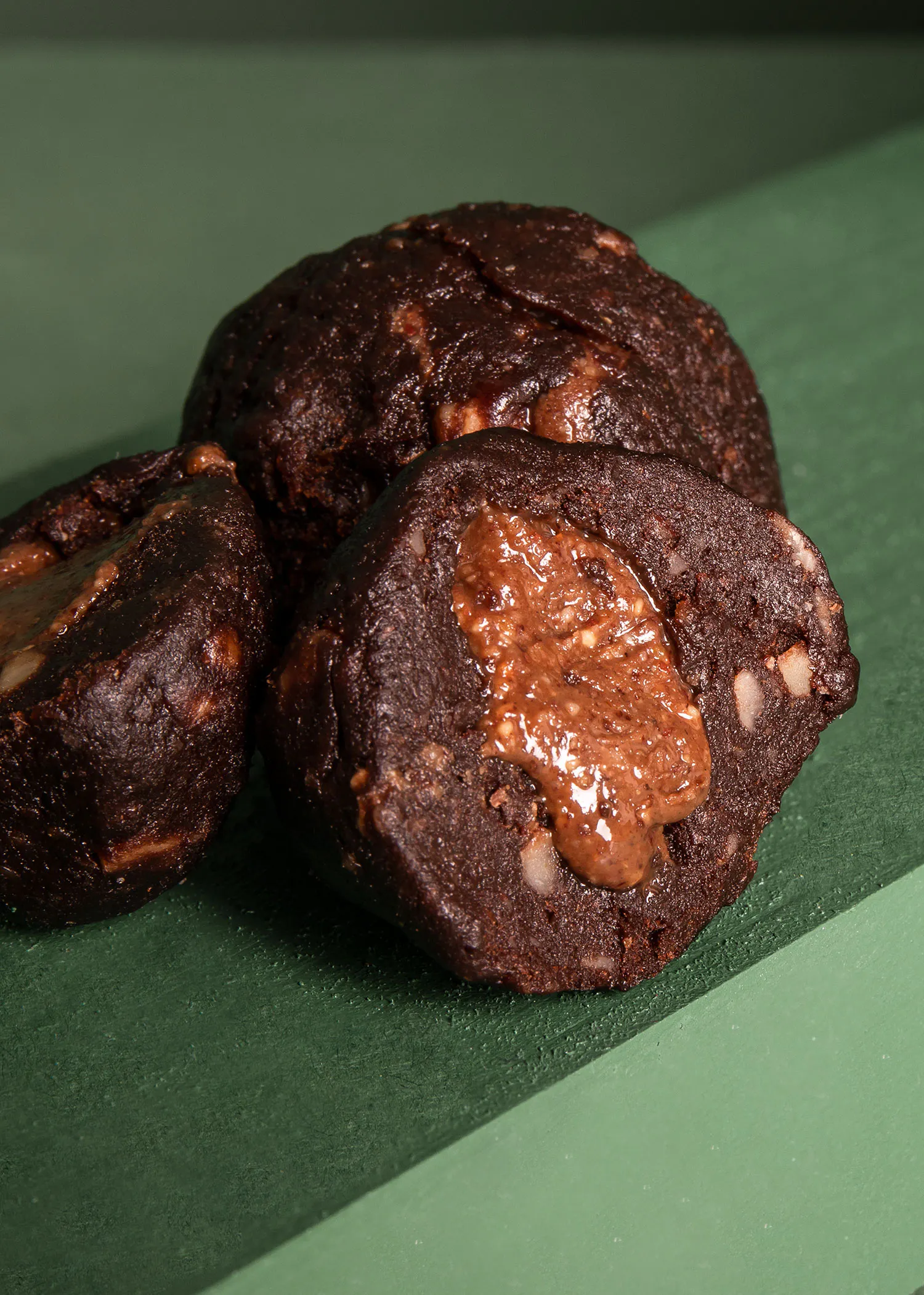 trois biscuits au chocolat sont posés sur une surface verte