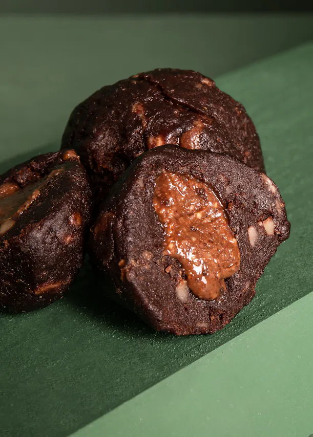 trois biscuits au chocolat sont posés sur une surface verte