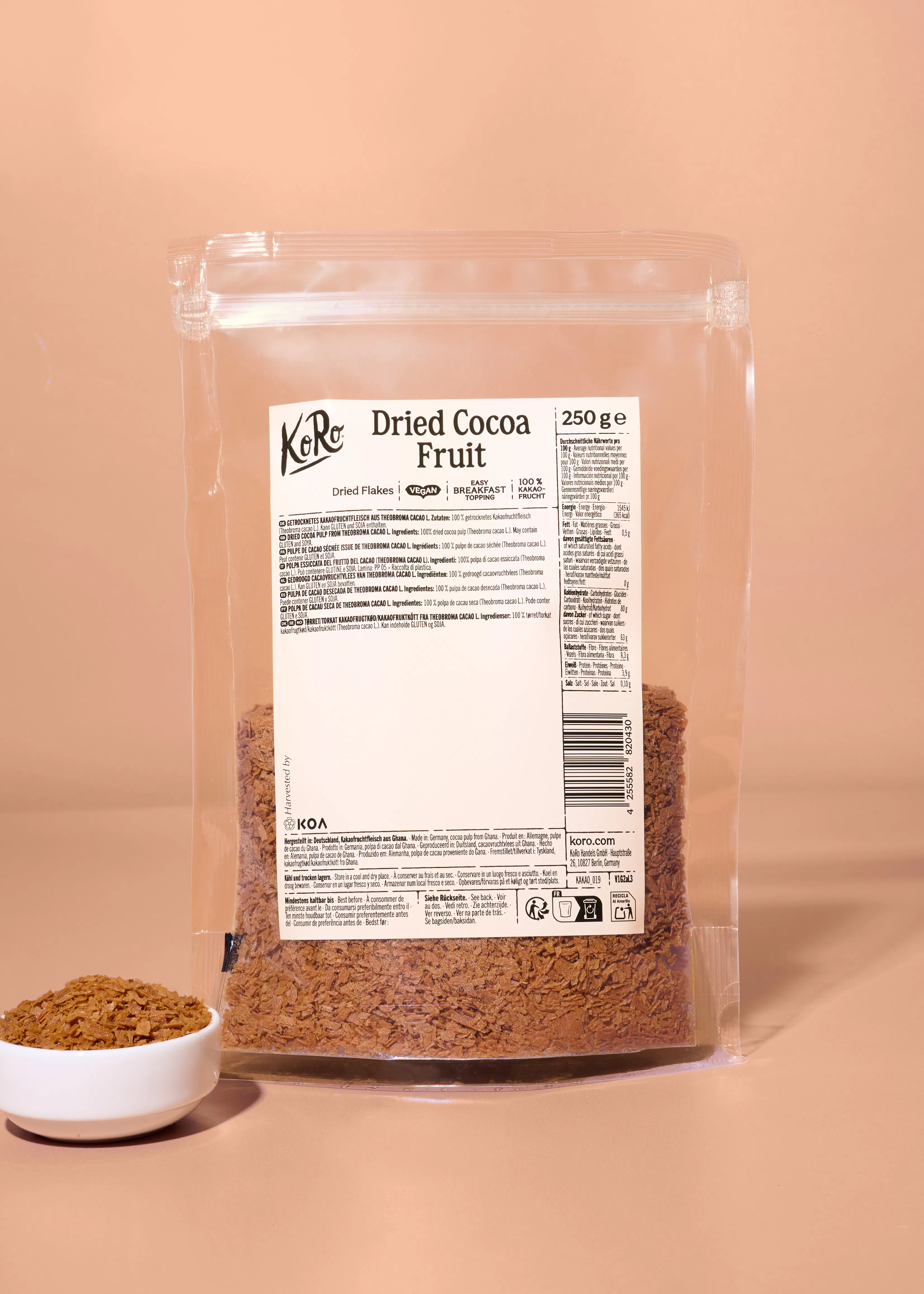 eine durchsichtige verpackung mit getrockneten kakaofruchtflocken der marke koro inklusive produktinformationen und nährwerttabelle auf der vorderseite.