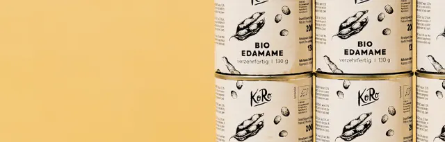 mehrere dosen koro bio edamame vor einem hellgelben hintergrund.
