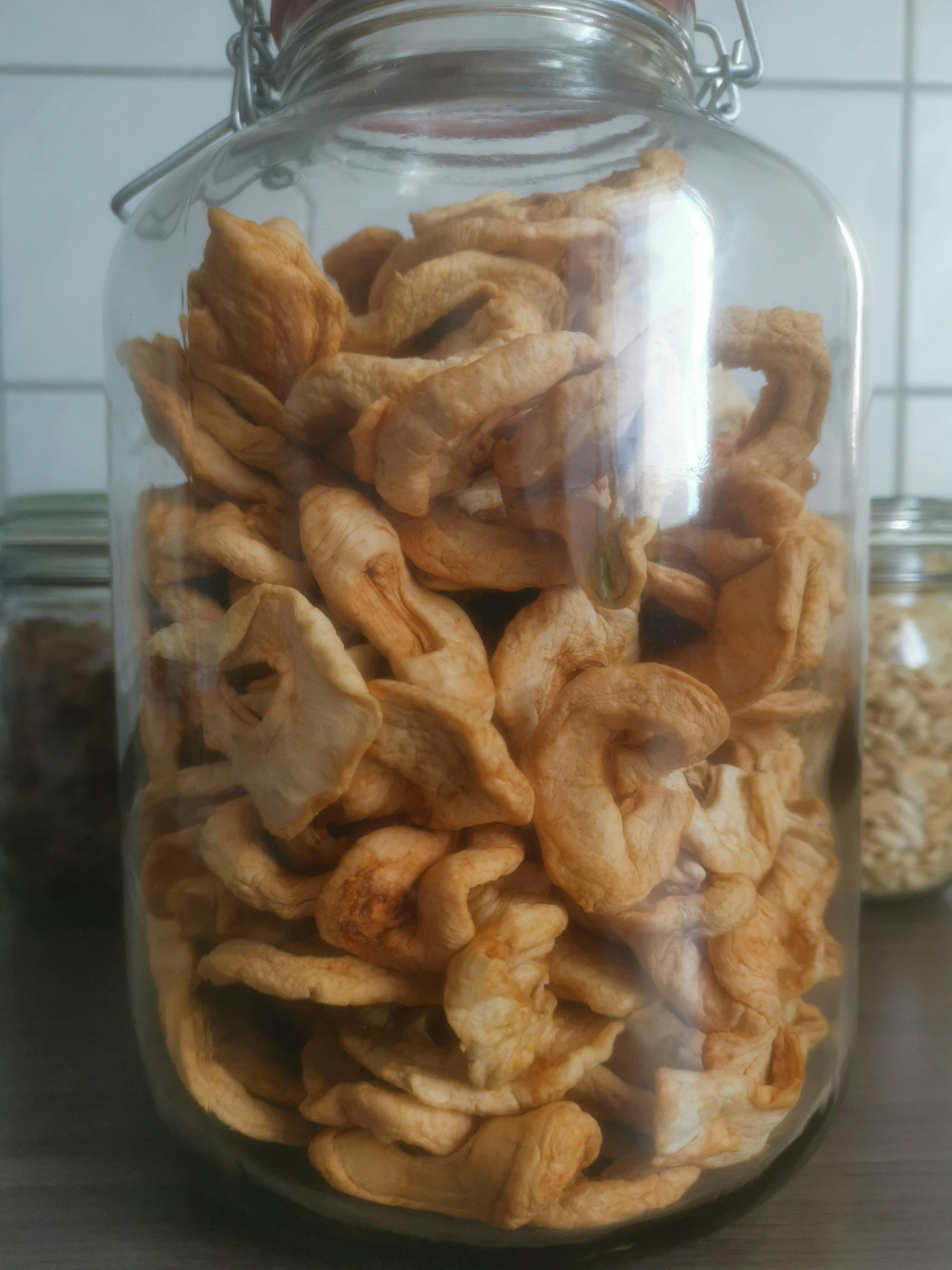 un gros bocal en verre rempli de pommes séchées