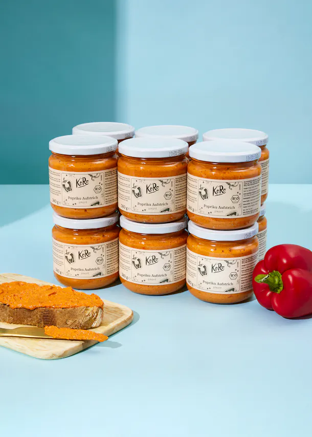 eine Reihe von Gläsern mit paprika aufstrich stehen auf einem Tisch