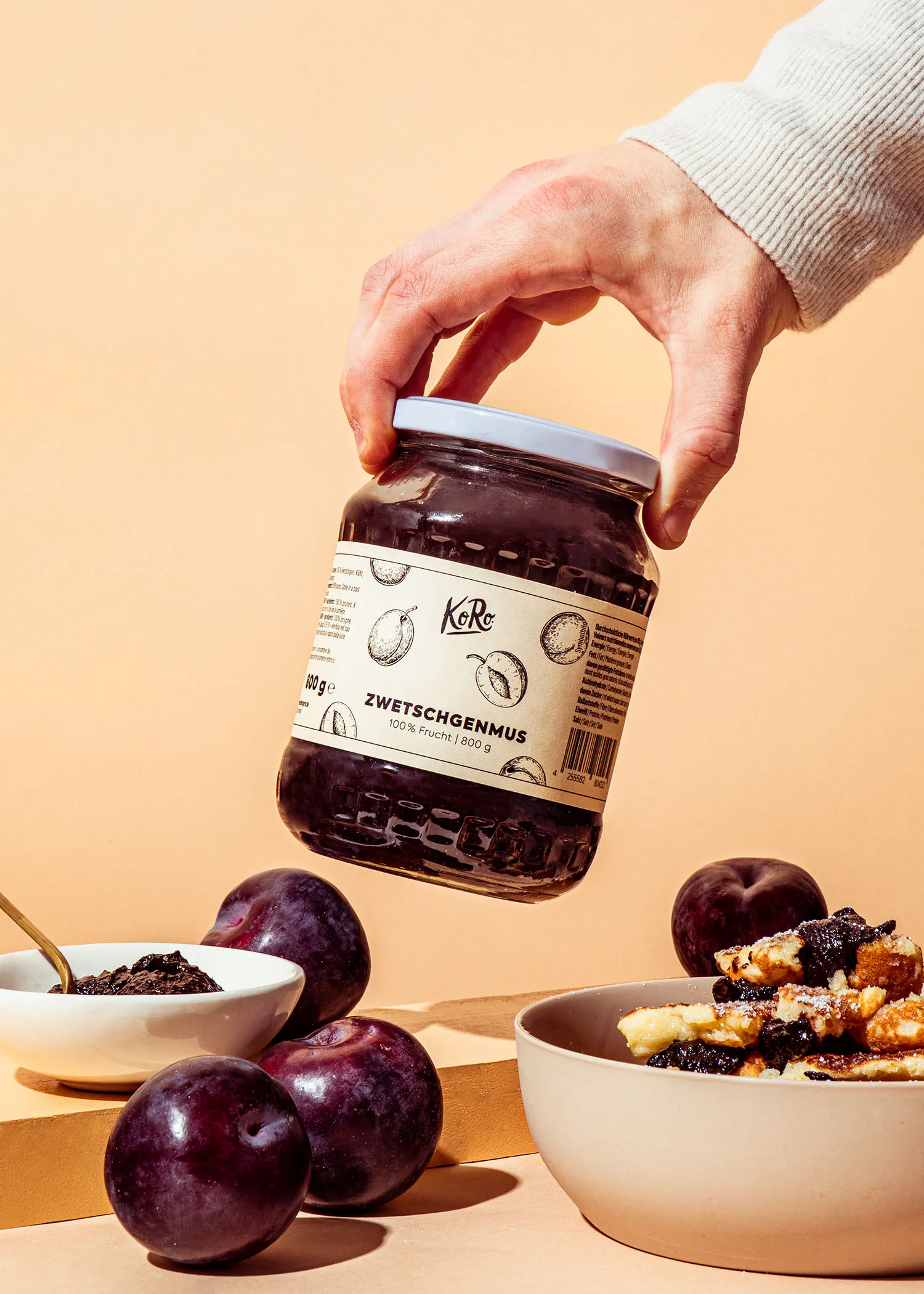a person is holding a jar of zwetschgenmus