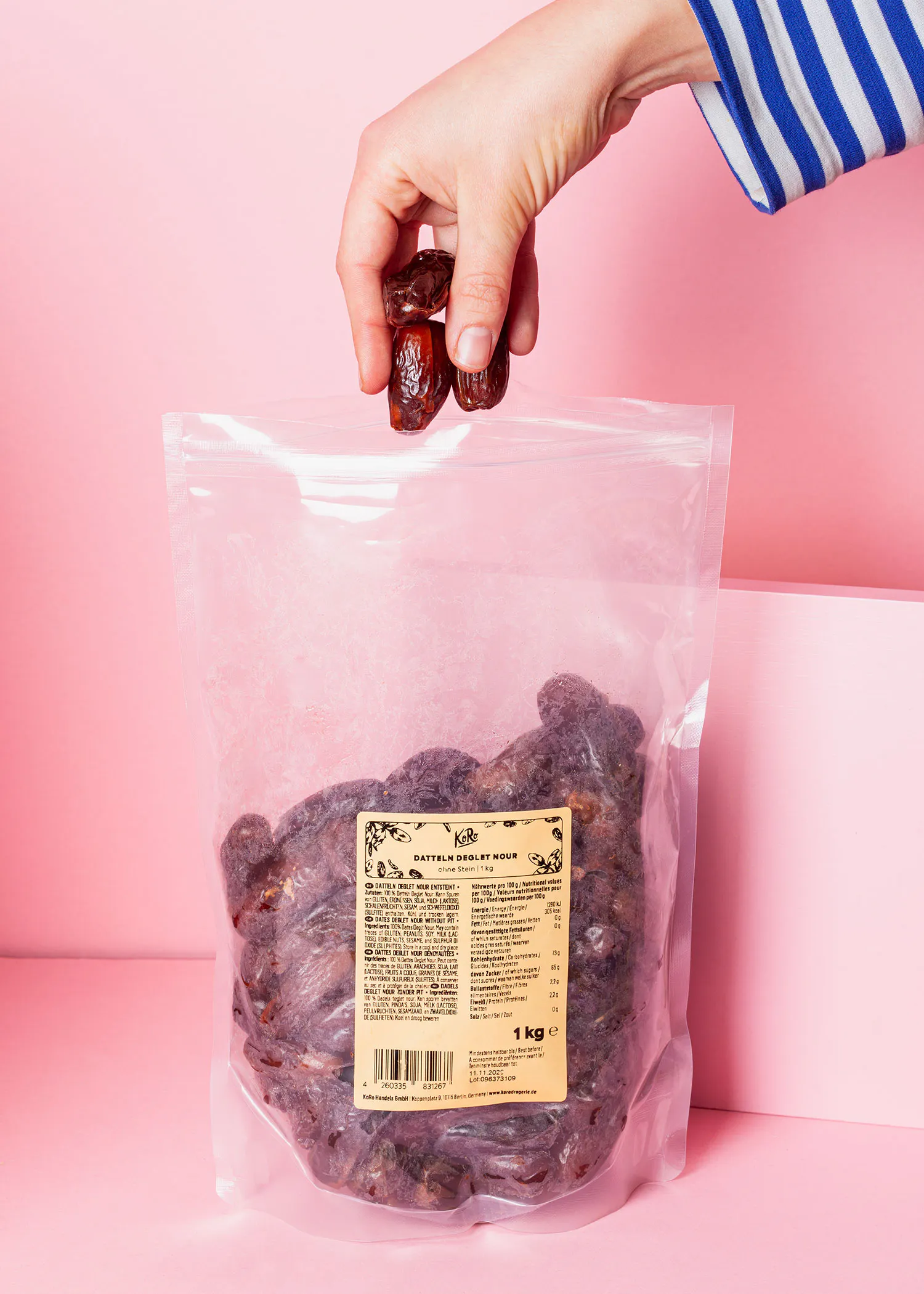 une personne tient une poignée de dattes dans un sac de 1 kg