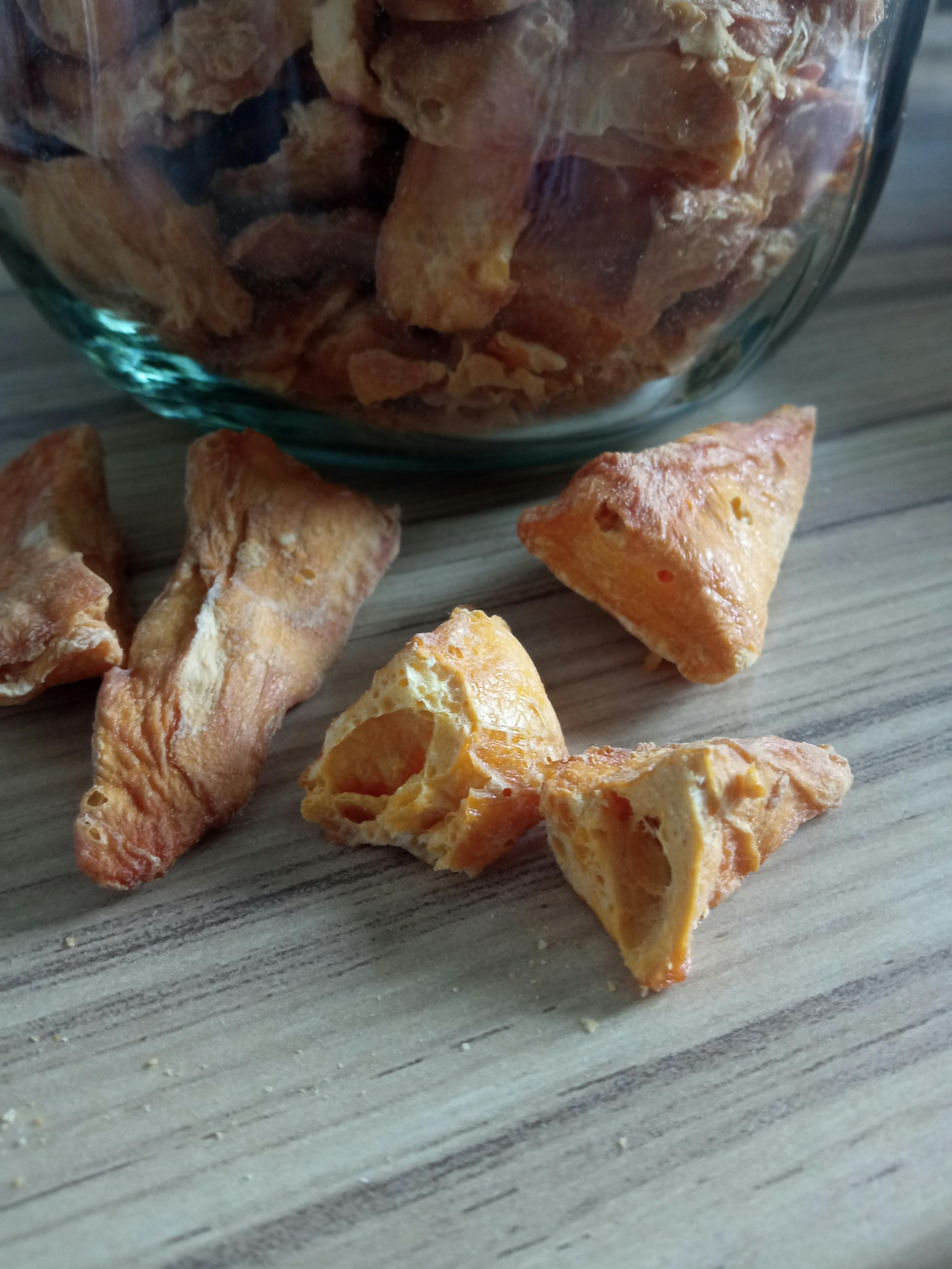 a glass jar filled with pieces of food on a wooden table