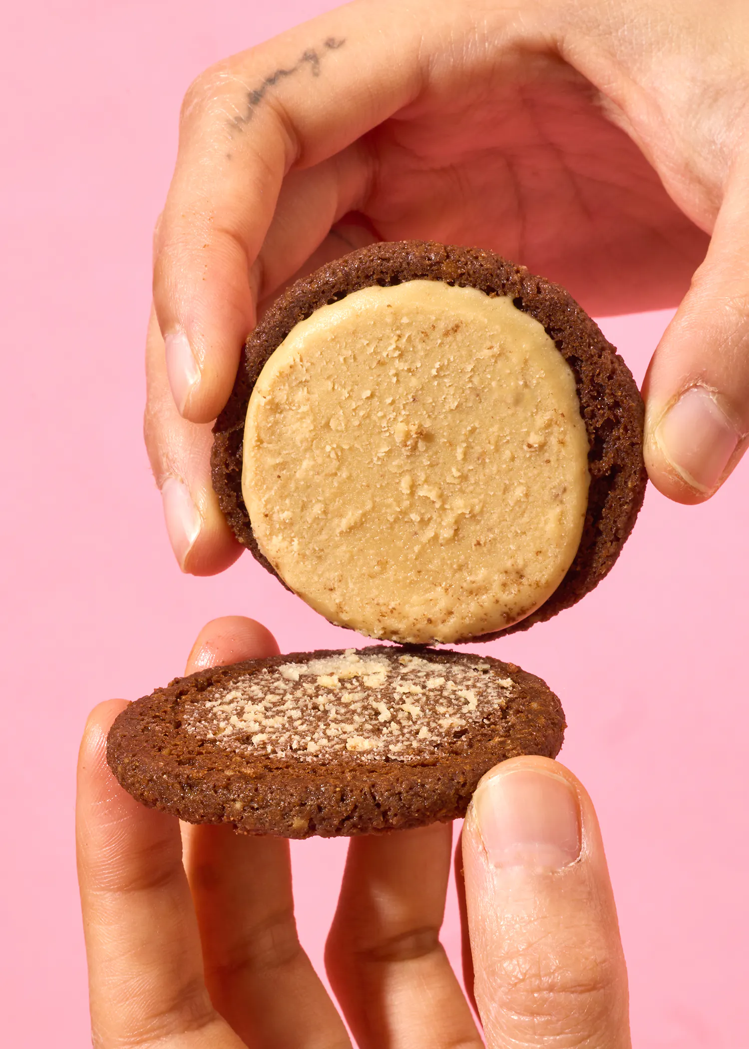 une personne tient un biscuit au beurre d' arachide à l' intérieur d' un autre biscuit