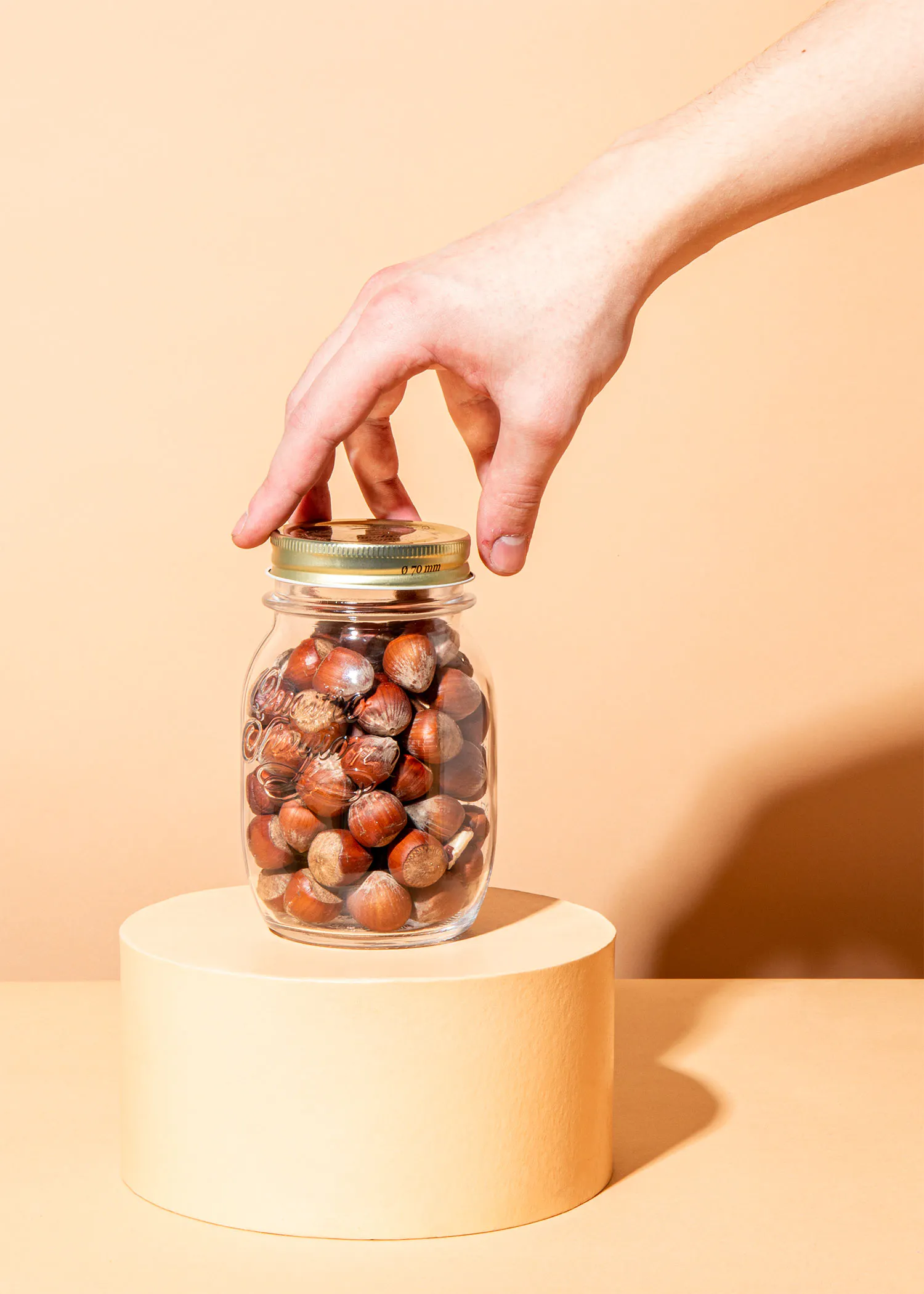 eine Hand greift nach einem Glas voller Haselnüsse