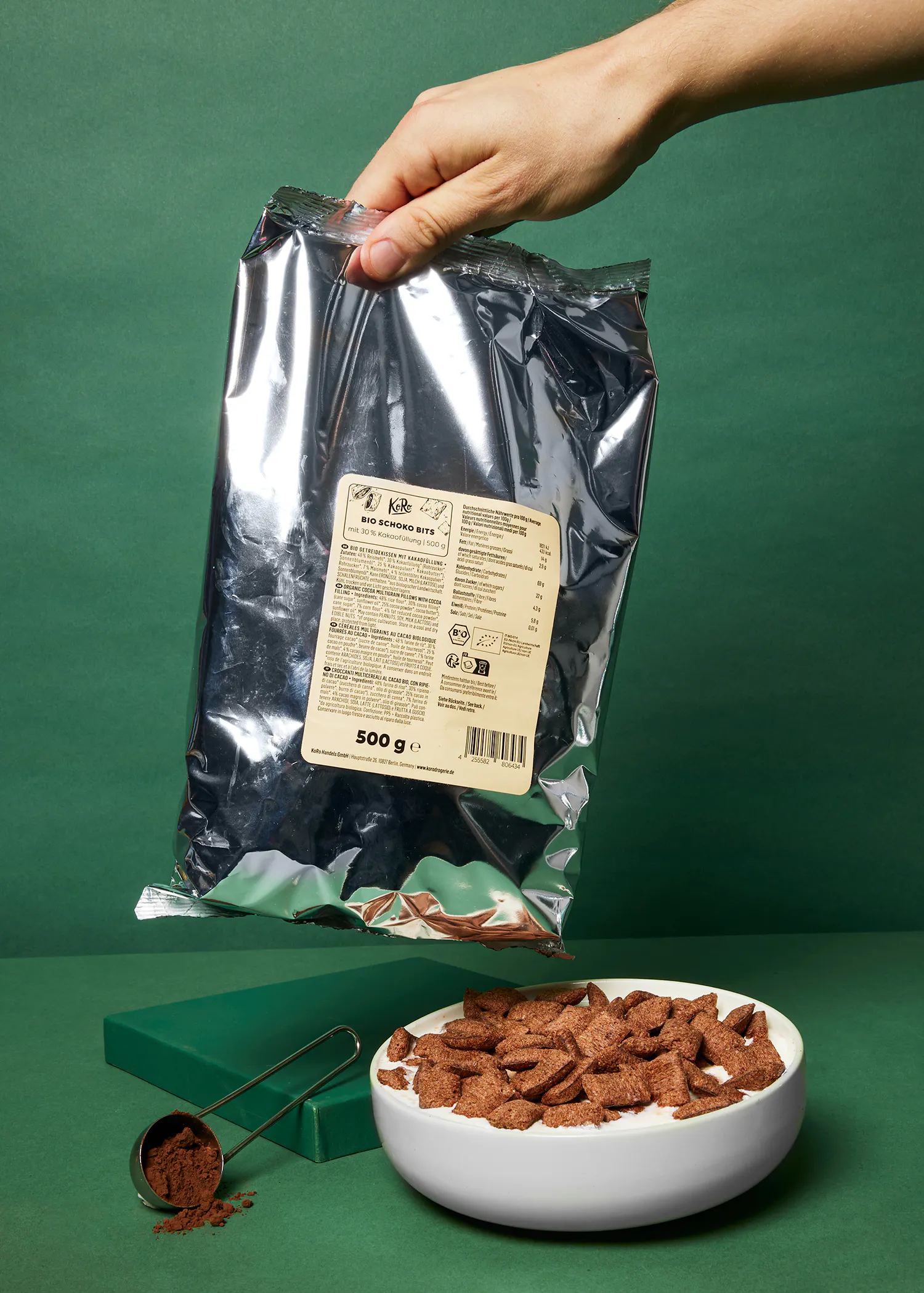 a person is holding a bag of cocoa flakes over a bowl of cereal