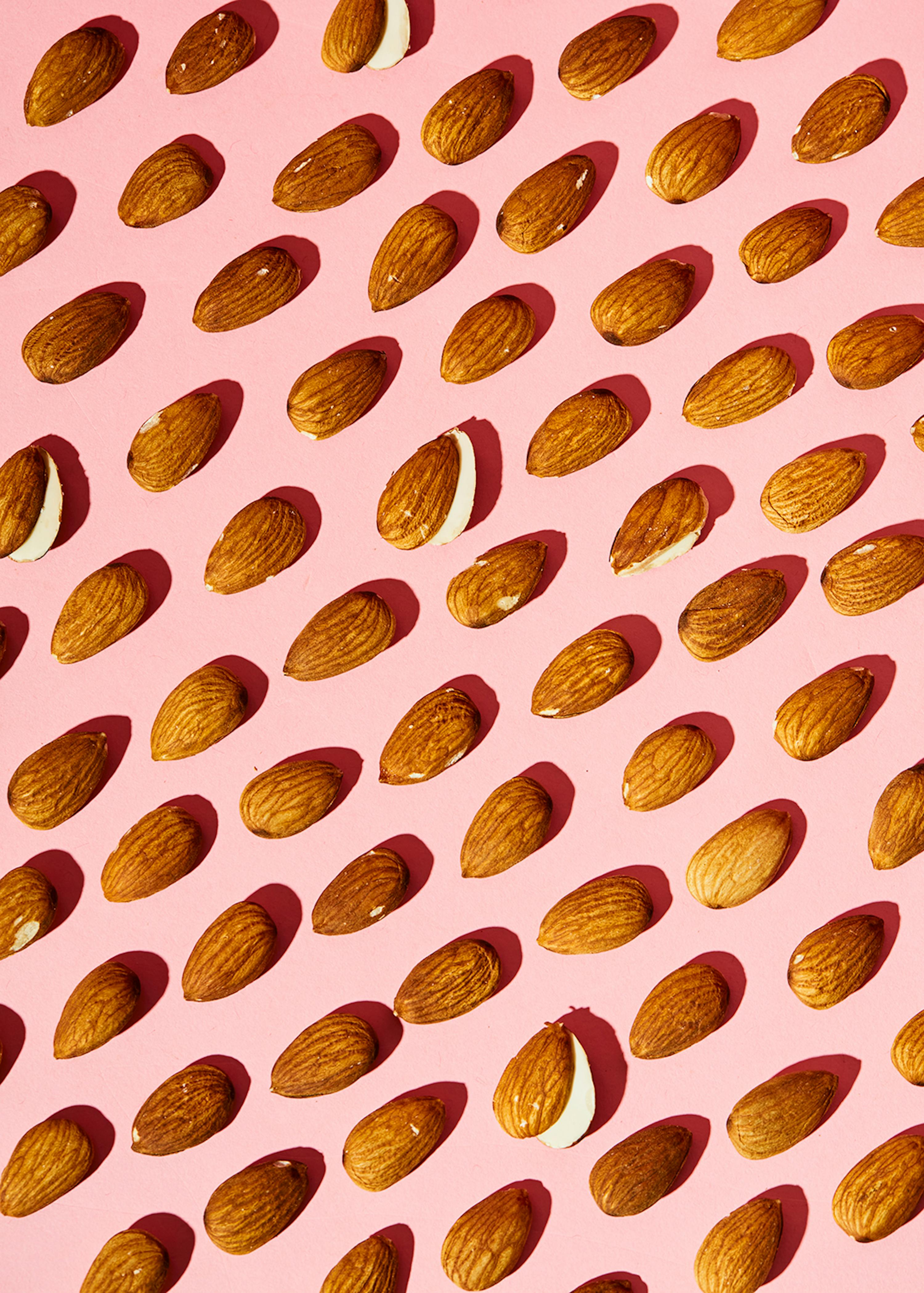 un modello di mandorle su sfondo rosa con una mandorla rotta