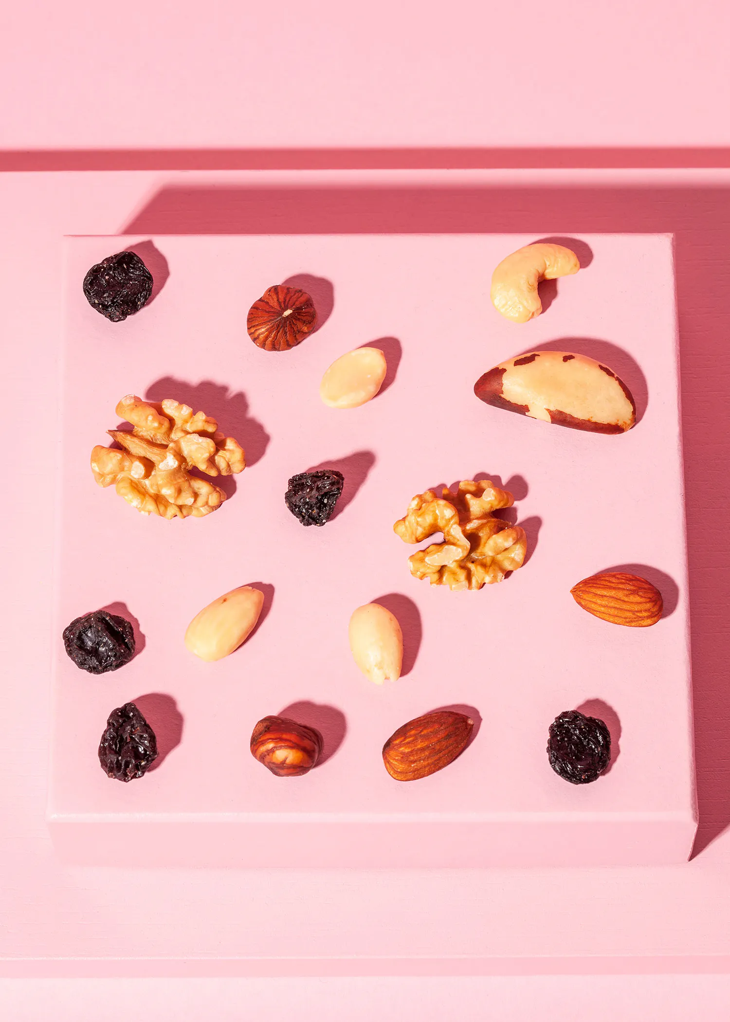 nuts and raisins are arranged on a pink surface