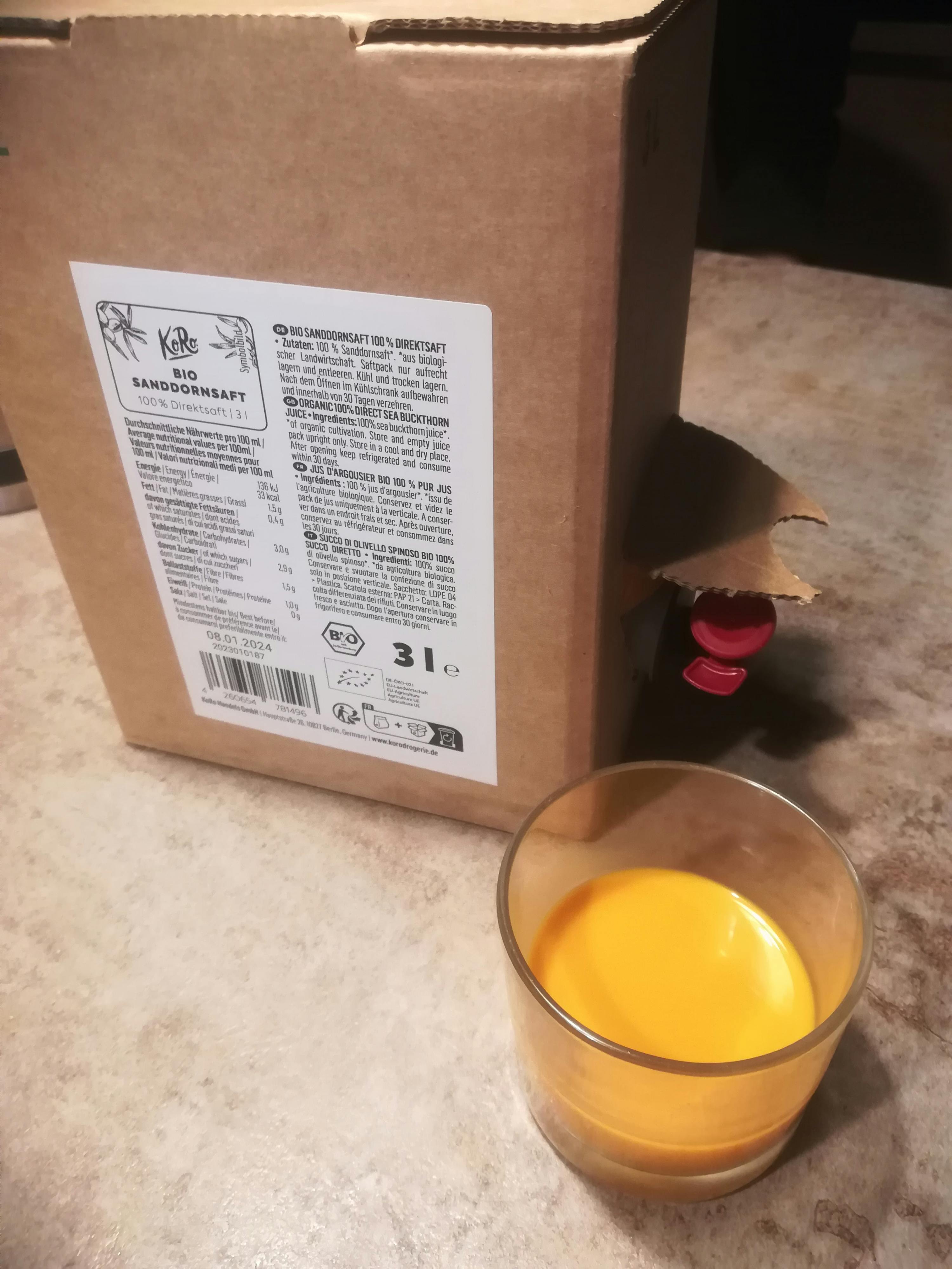 un bicchiere di liquido giallo è seduto accanto a una scatola di cartone