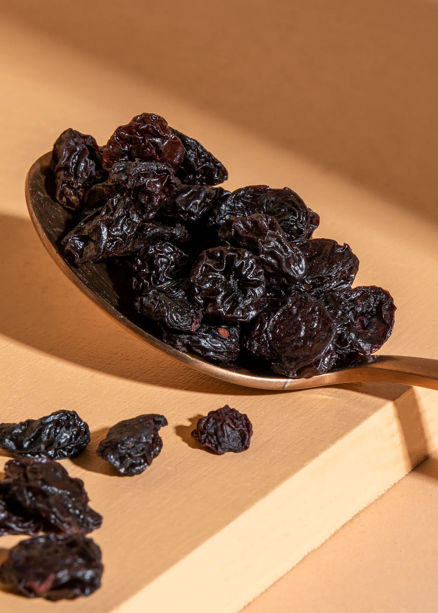 a spoon full of black raisins sits on a table