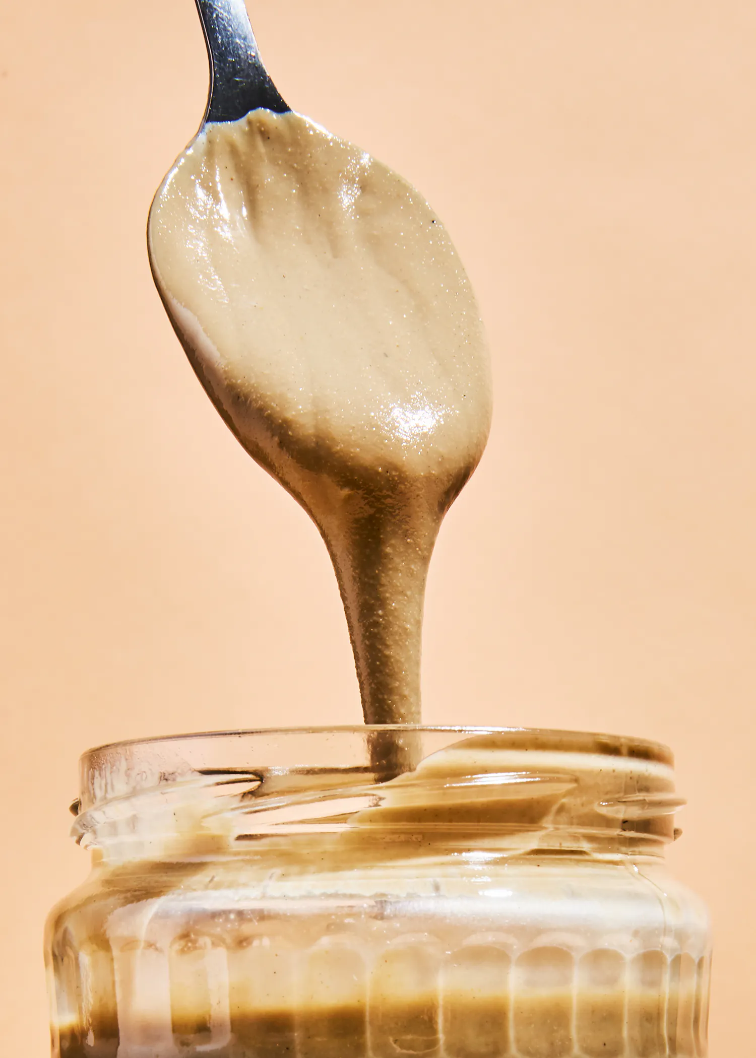 Ein Löffel Erdnussbutter wird in ein Glas gegossen