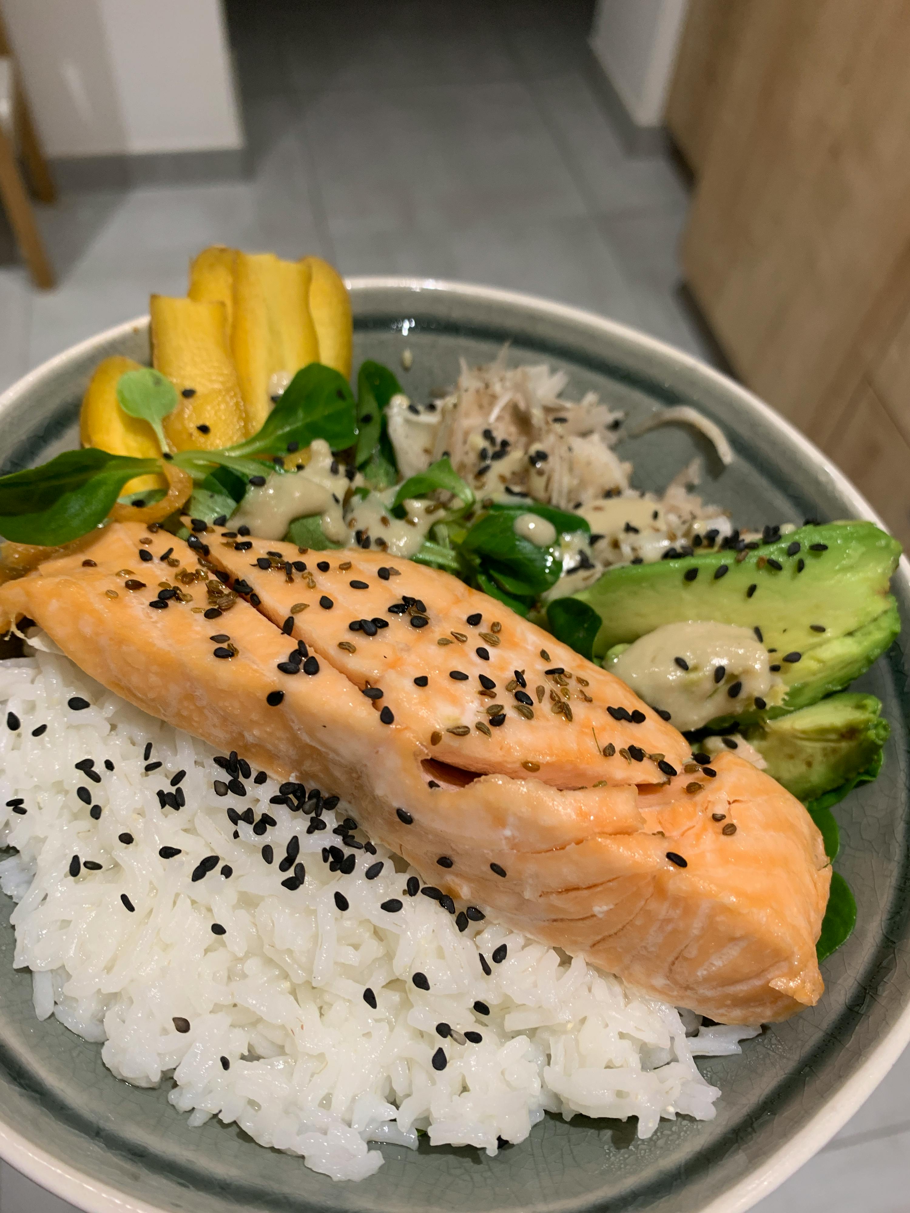 a plate of food with rice avocado and sesame seeds