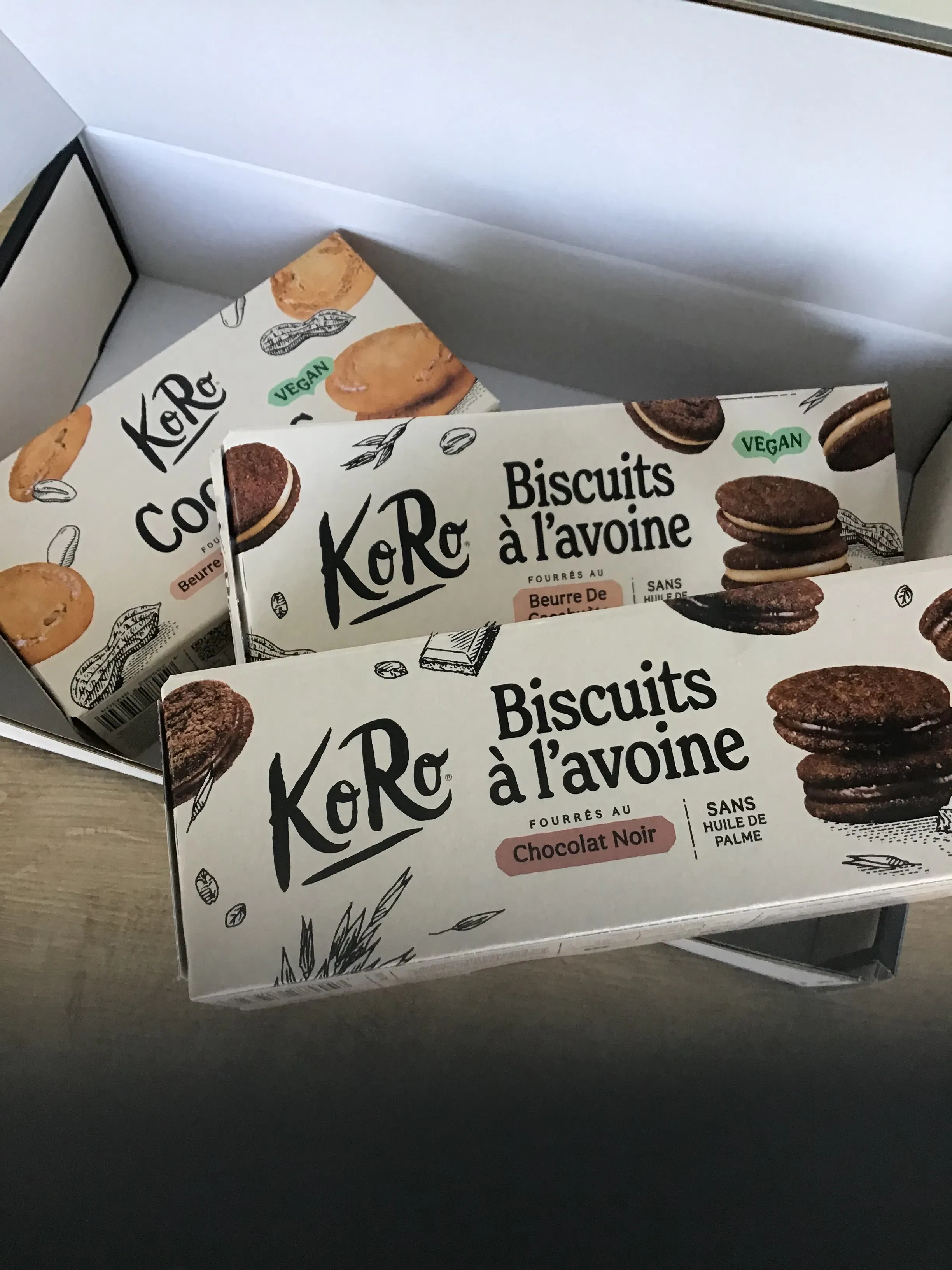 tre confezioni di biscotti all'avena koro con diversi gusti disposte all'interno di una scatola di cartone.