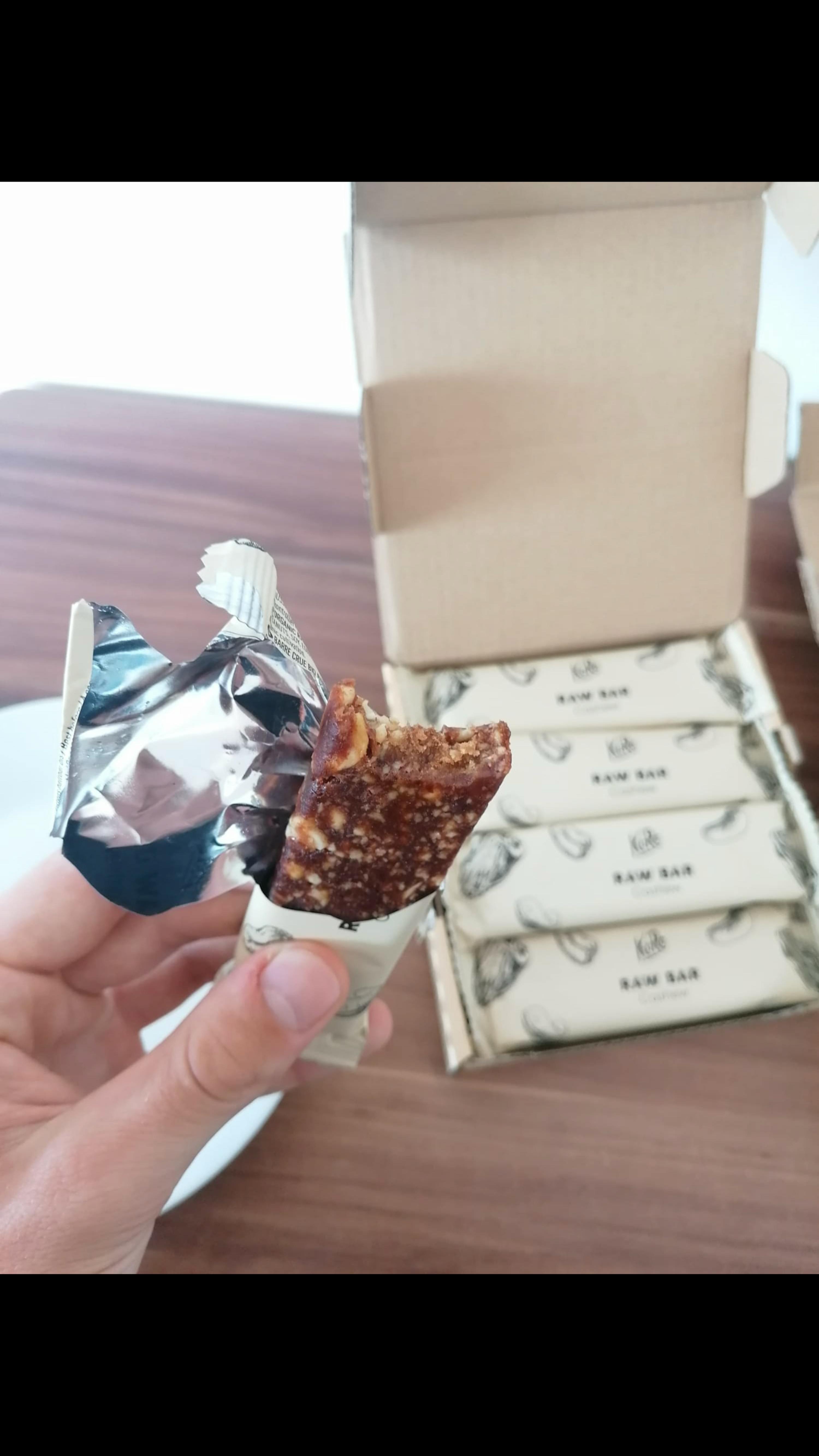 una persona tiene in mano una barretta di cioccolato raw bar