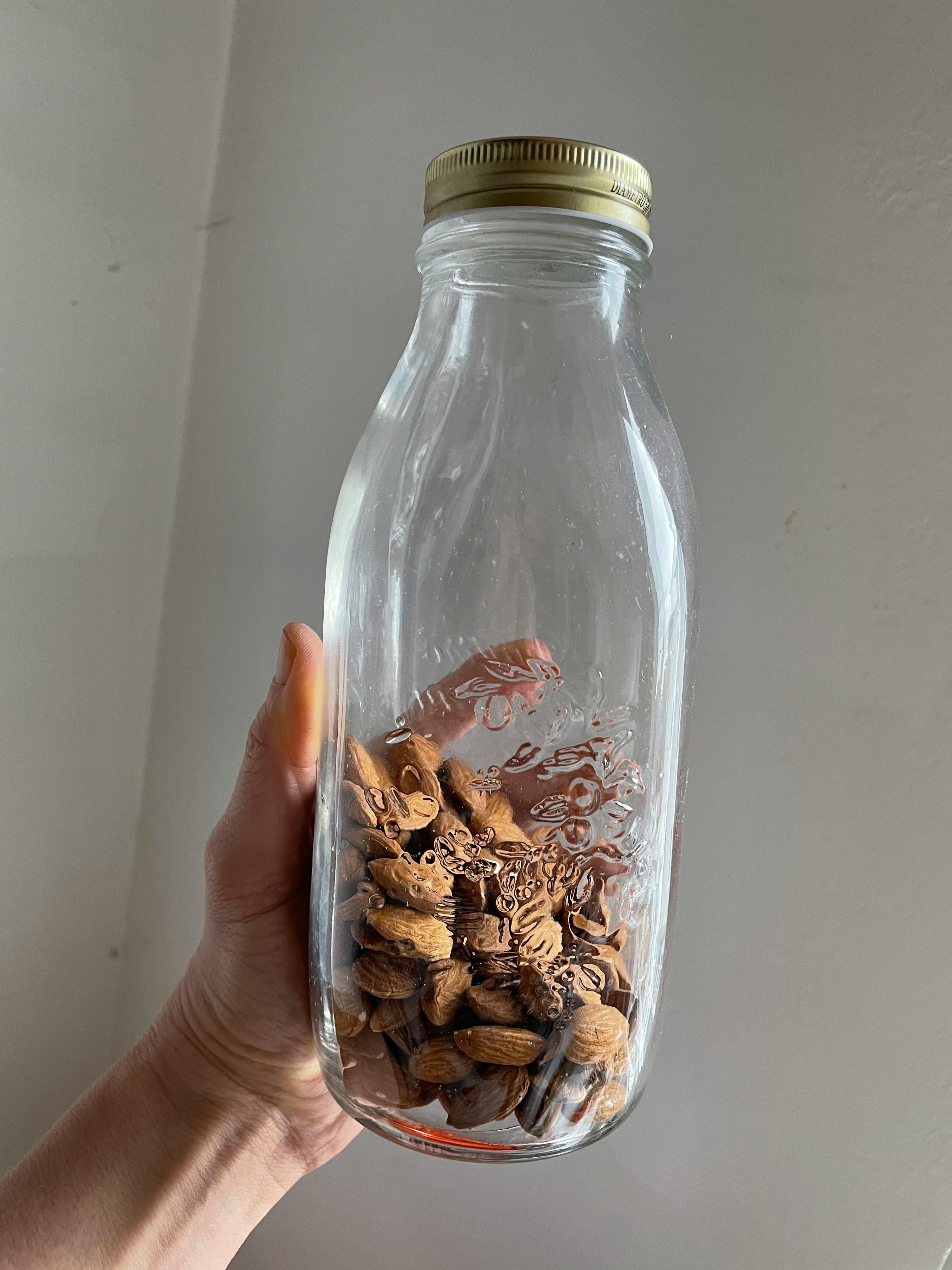 a hand is holding a mason jar filled with almonds