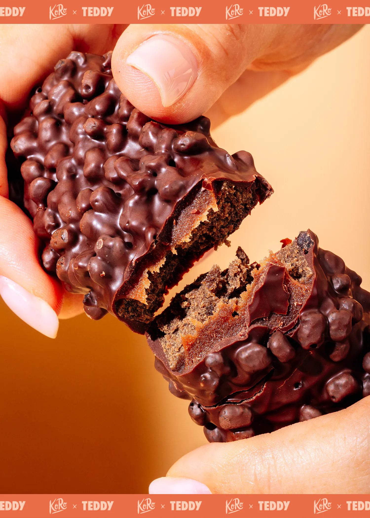 une main tient une barre chocolatée à la surface bosselée, cassée en deux pour révéler un intérieur brun et friable.